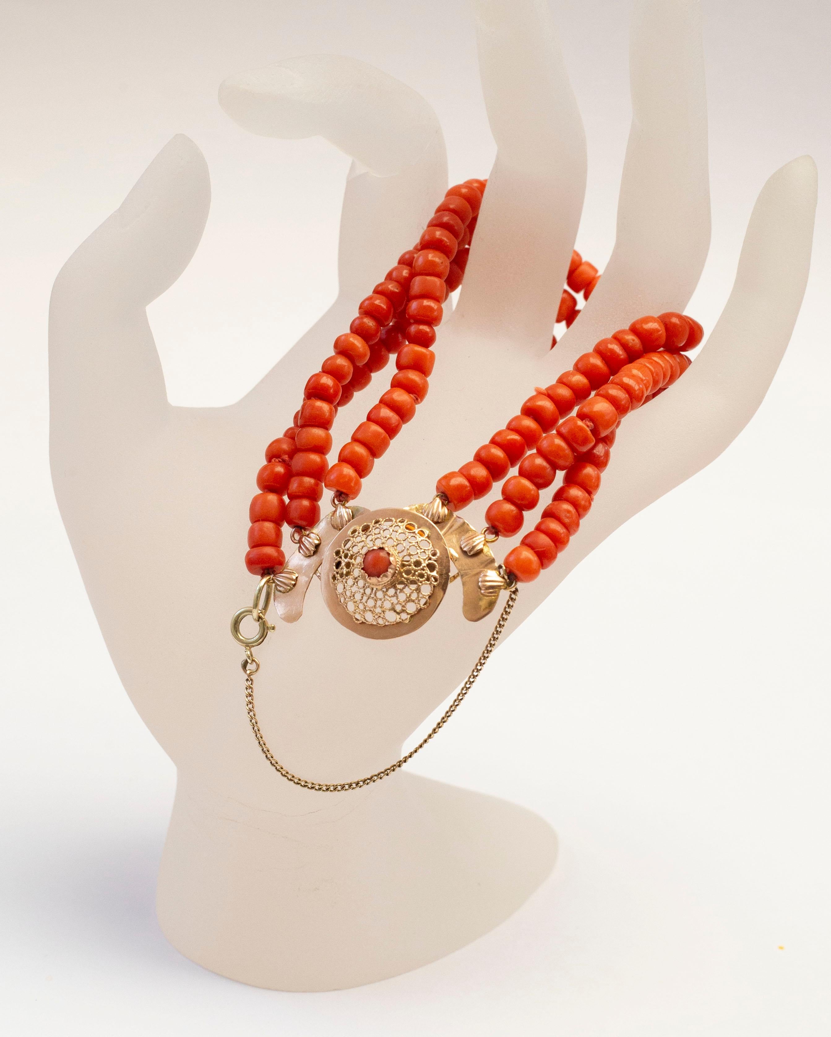 An antique 3-row natural not dyed red coral bracelet with round filigree 14 karat yellow clasp with red coral bead in the centre. The clasp features a 14k gold safety chain. The clasp does not have a gold content mark, but it was professionally