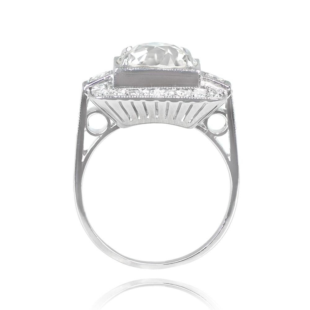 This antique Art Deco ring showcases a 3.07-carat old European cut diamond with K color and VS1 clarity. The center diamond is elegantly secured by prongs within a raised square bezel. Two smaller diamonds in square bezels flank the center stone,