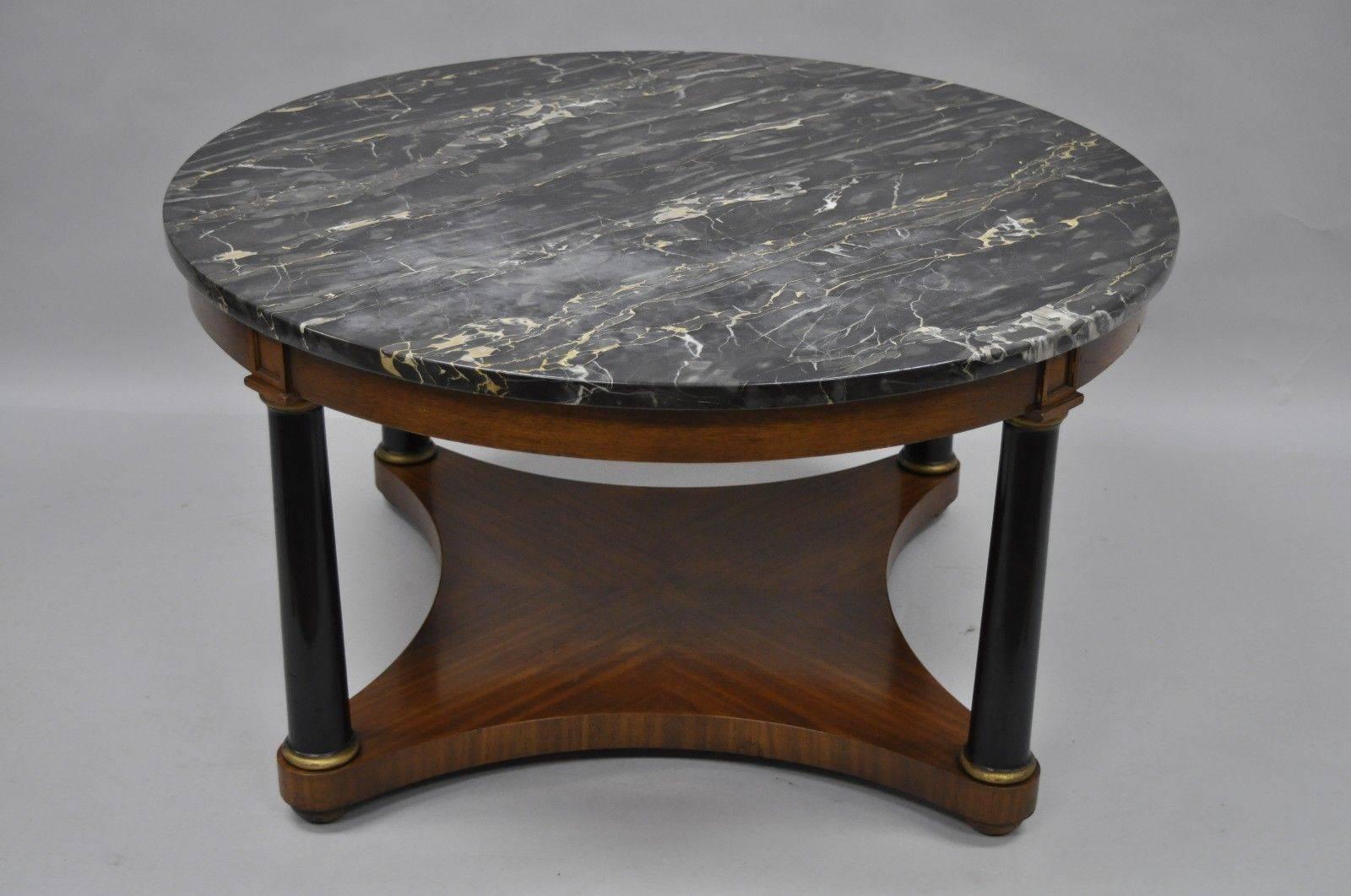 Antique round marble-top Empire style coffee table. Item features black marble top, black columns, lower shelf, bun feet, gold accents, original Holzheimer Interiors tag which is/was a high end interior design firm. Measurements: 20.5