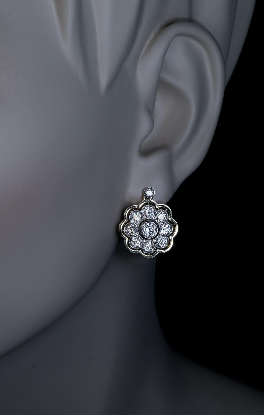 Circa 1920

These finely crafted 18K greenish-yellow gold and platinum cluster earrings are embellished with well-matched, bright white old mine cut and old European cut diamonds (E-F color, VS-SI clarity). The diamond and platinum clusters are