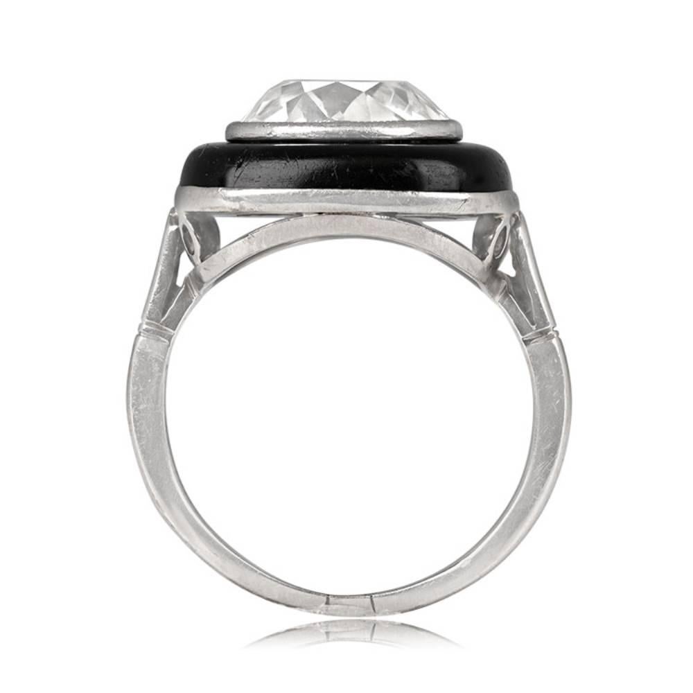This exquisite 18k white gold Art Deco ring features a 4.30-carat cushion cut diamond with K color and SI1 clarity. The diamond is elegantly bezel-set in buffed onyx, adding a striking contrast. The ring is further enhanced with intricate milgrain