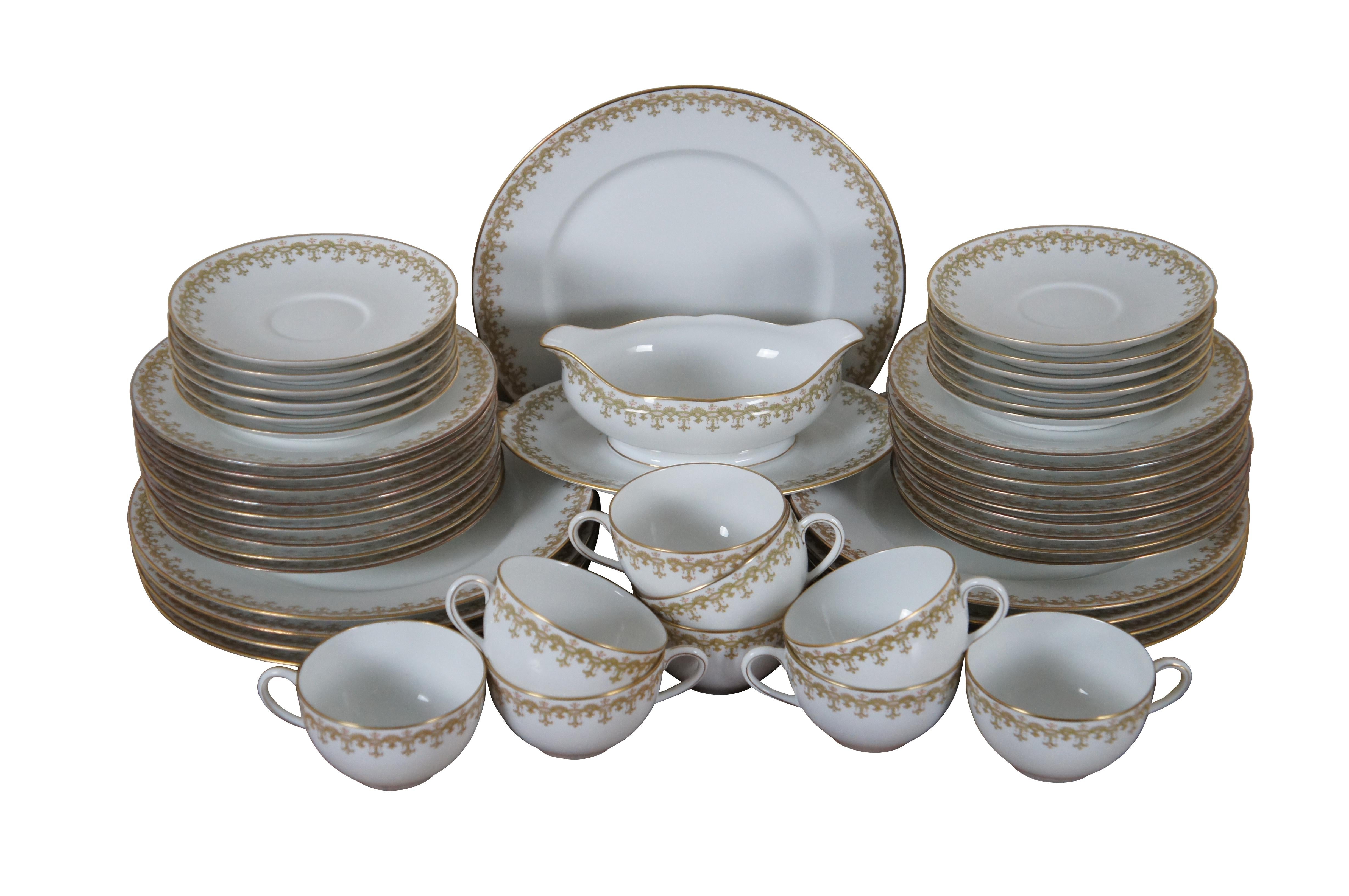 49 piece partial set of Limoges porcelain dinnerware by Charles Ahrenfeldt featuring gilded edges and a printed patterned border of interlocking swags in a light golden-green. Marks used from circa 1894-1930’s.


