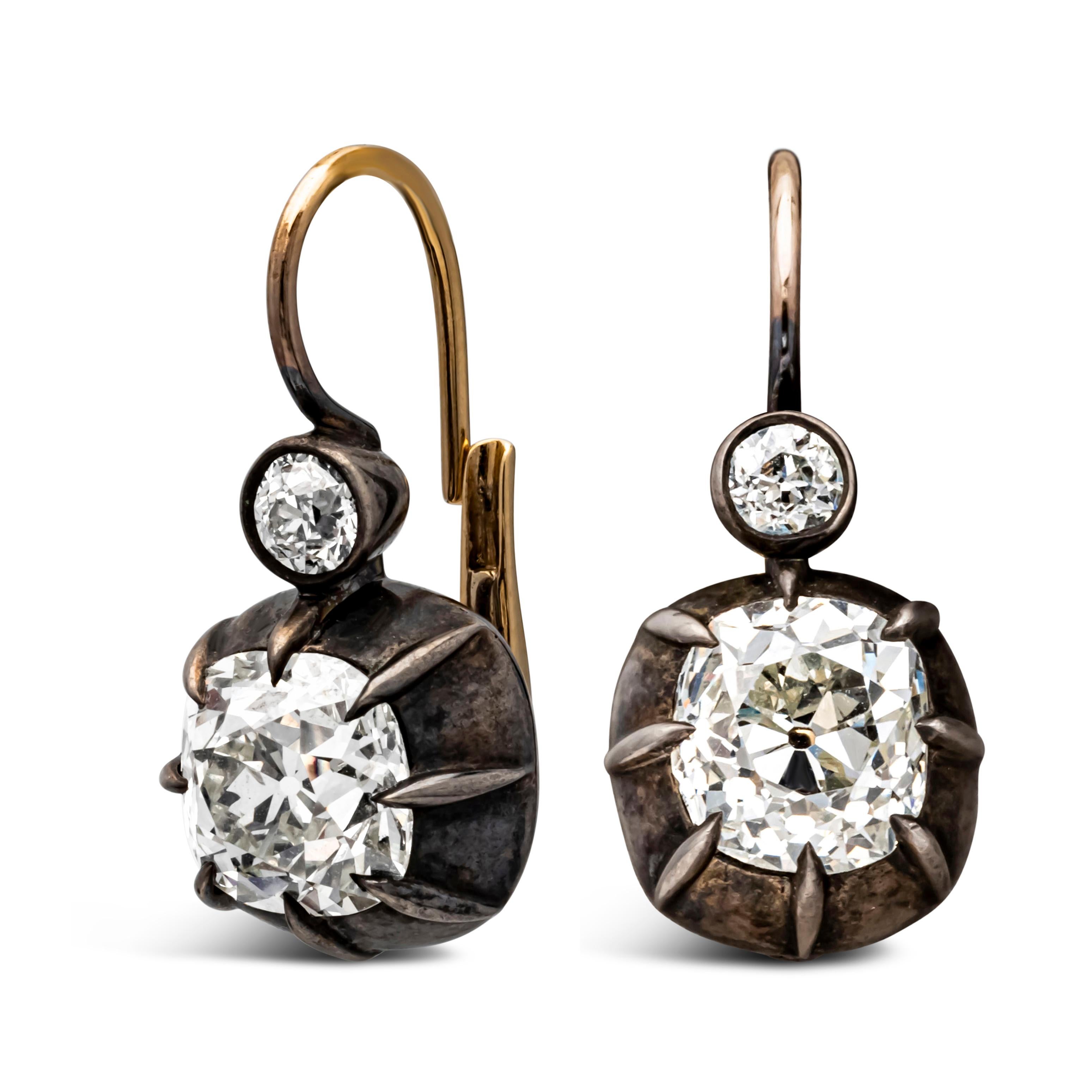 A simple yet elegant pair of antique dangle earrings, featuring two old mine cushion cut diamonds weighing 2.34 carats and 2.63 carats with approximately I-J color and VS-SI clarity, respectively. Accented with two small old European cut diamonds