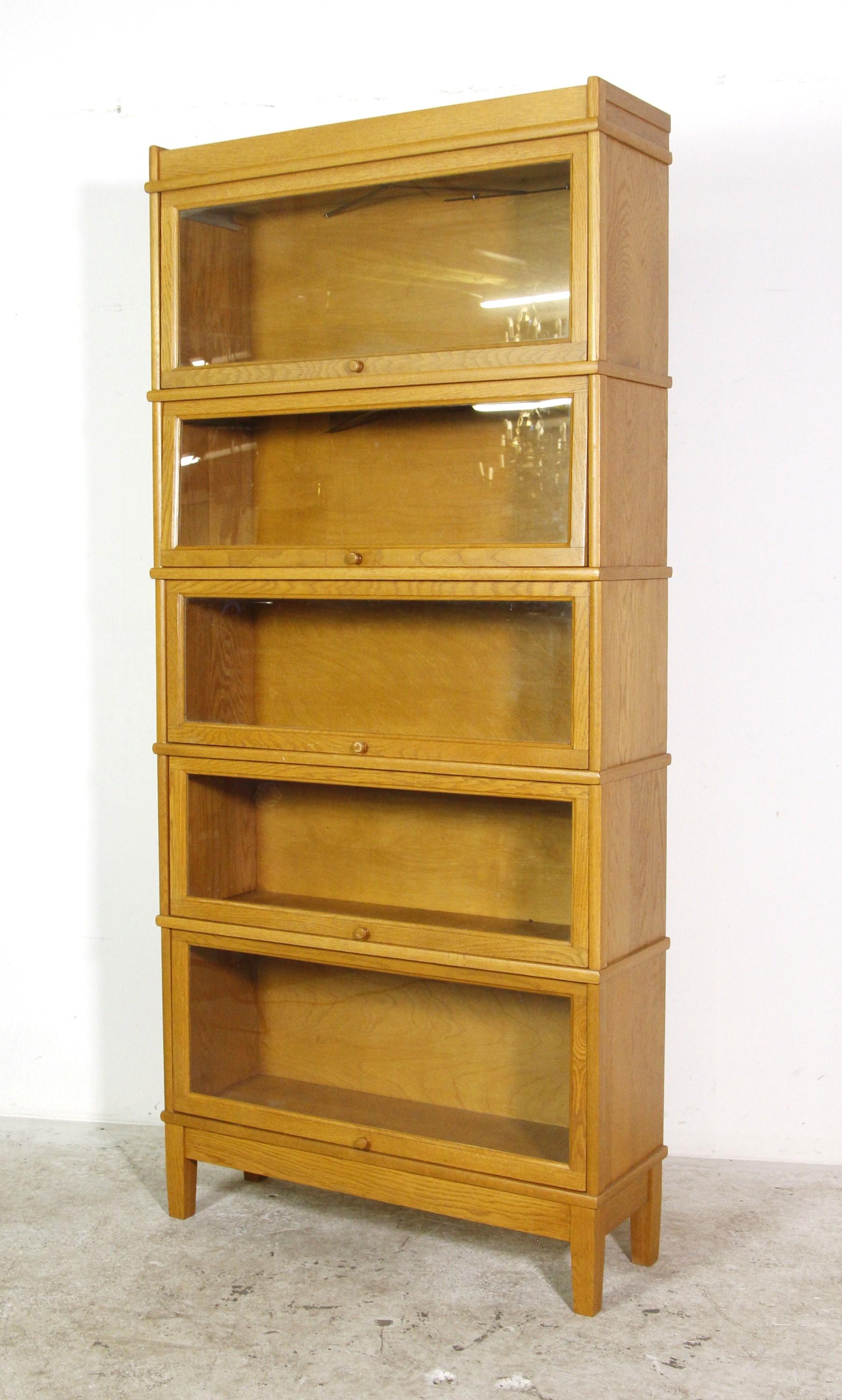 Solid oak 5 section, stacking barrister bookcase with sliding glass fronts and wooden pulls. This antique bookcase has good working glass doors, and all the original glass is intact. Please note, this item is located in one of our NYC locations.