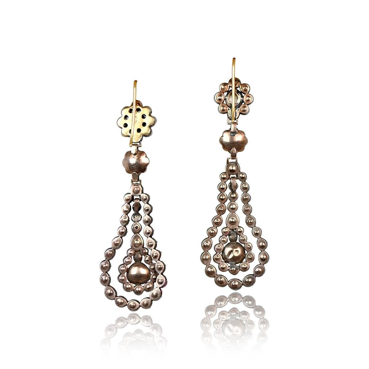 A lovely pair of antique diamond earrings with silver on gold mounting from the Georgian era, circa 1810. Each earring features a suspended antique pear-shaped rose-cut diamond, surrounded by a double oval halo of rose-cut diamonds. The total
