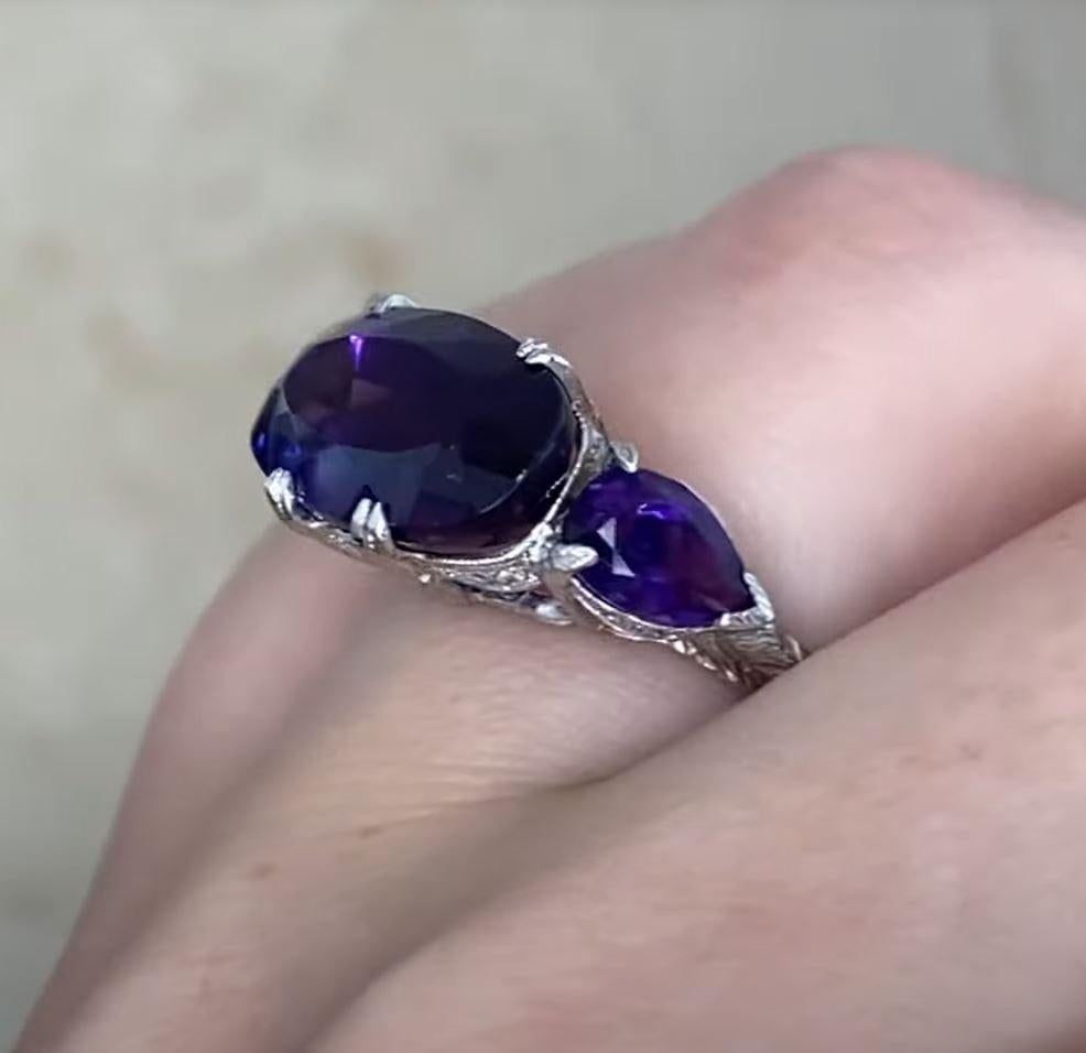 This striking ring features a prominent, elongated oval-cut amethyst weighing approx 5.30-carats, set in a sleek east-to-west orientation, which enhances its unique and contemporary appeal. The vibrant central amethyst is complemented by two smaller