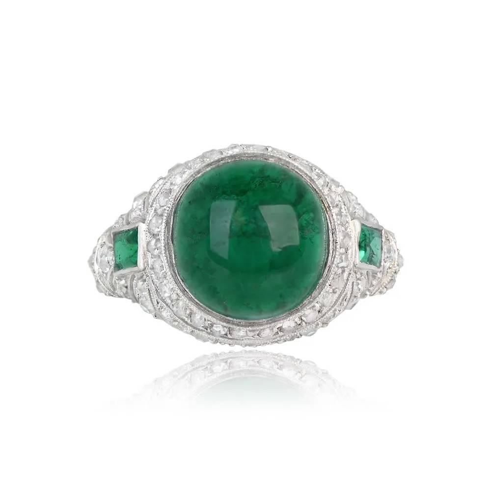 A stunning Art Deco ring with a 5.46-carat cabochon emerald as the centerpiece. Adorned with geometric open-work, old European cut diamonds, and rose-cut diamonds, the ring also features two natural emerald-cut emeralds on either side, each weighing