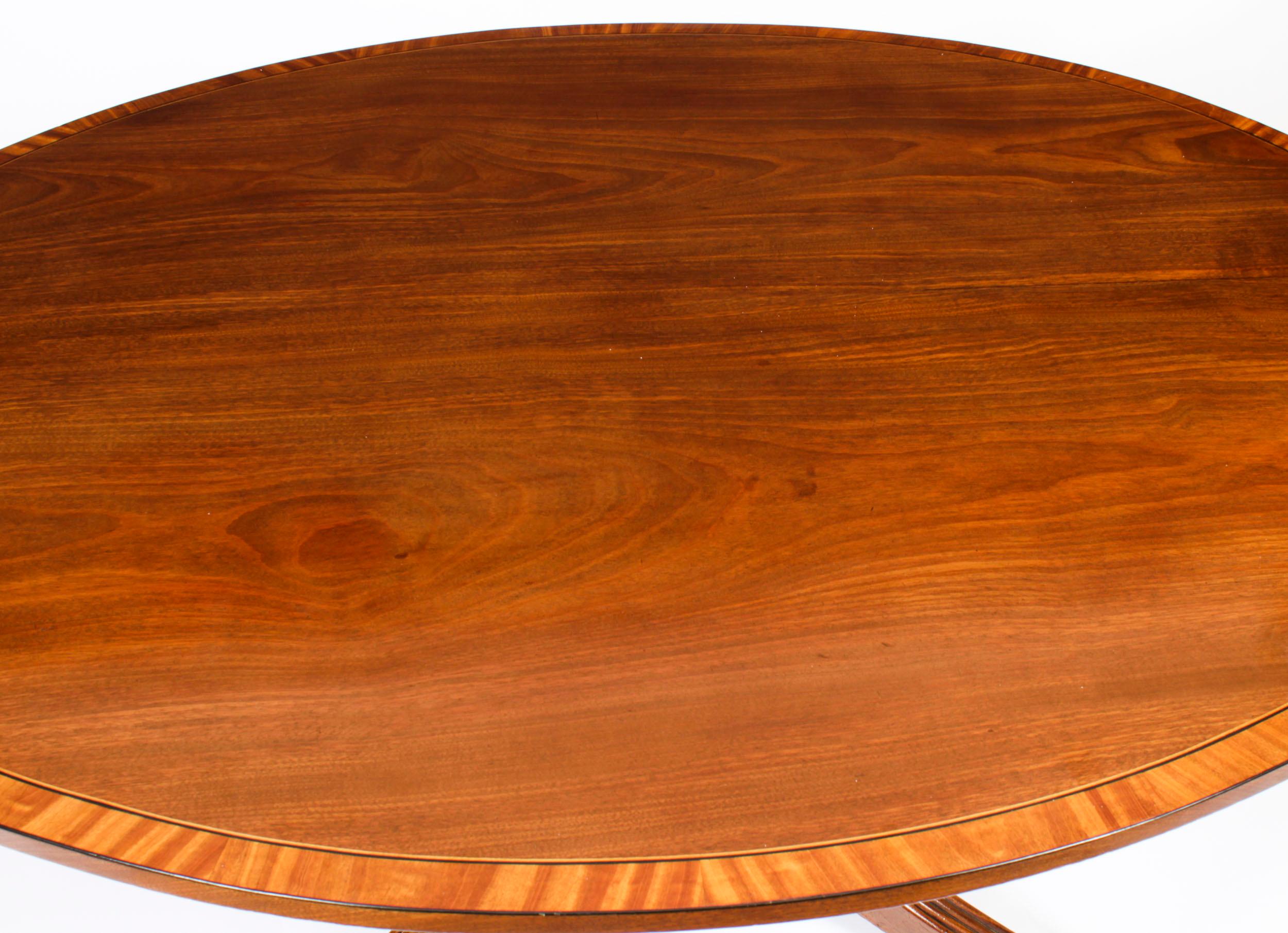 This is a beautiful antique Regency flame mahogany and Satinwood banded tilt top oval dining table dating from Circa 1820. 
 
The fabulous 5ft flame mahogany tilt top table can seat six people in comfort. The top is decoratively crossbanded in
