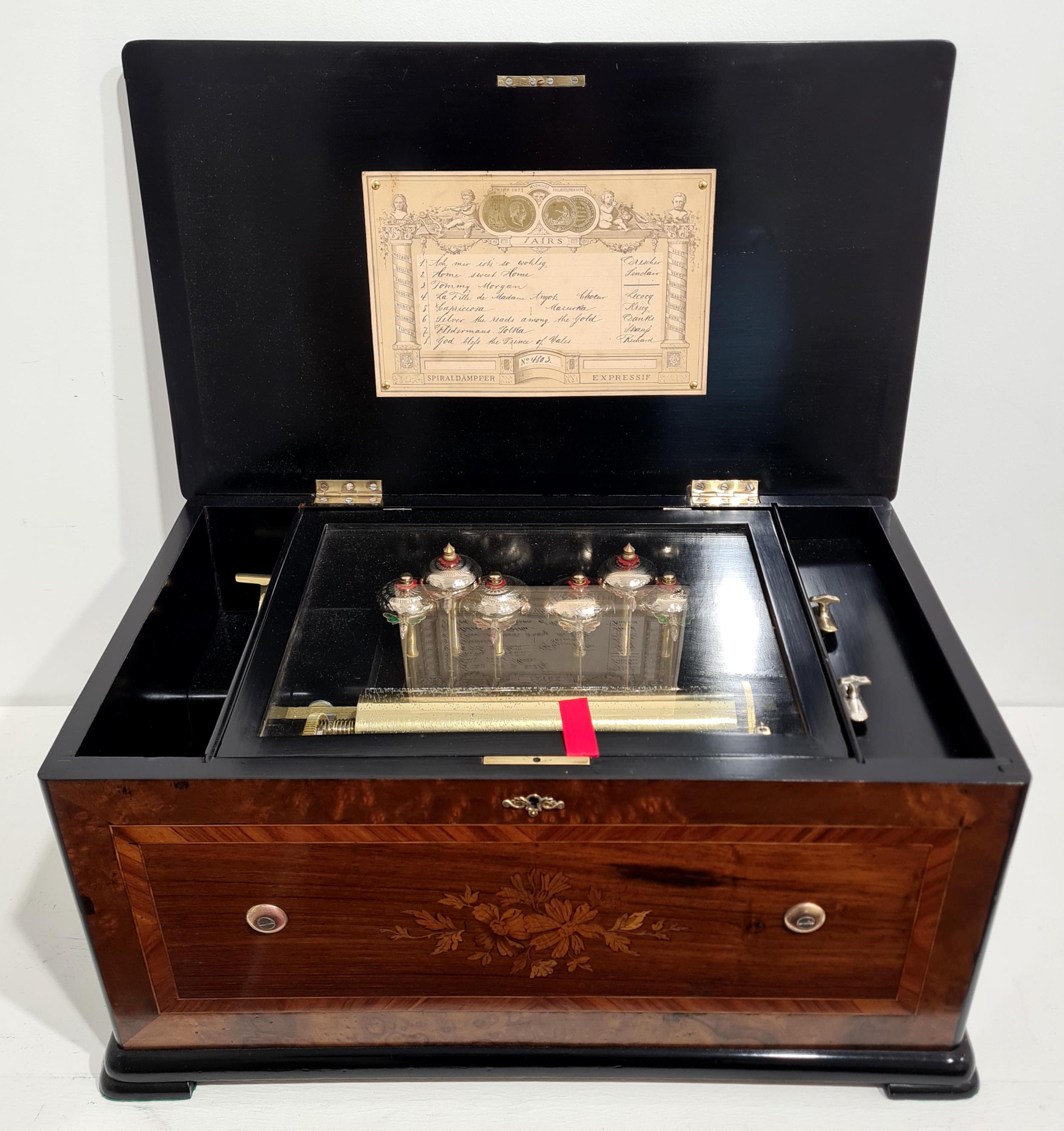 A lovely quality antique music box made by Karrer of Geneva, Switzerland in c. 1875. 
The fully serviced musical movement features a highly attractive arrangement of 6 individually engraved bells struck by colourful enamel bee strikers. 
It plays a