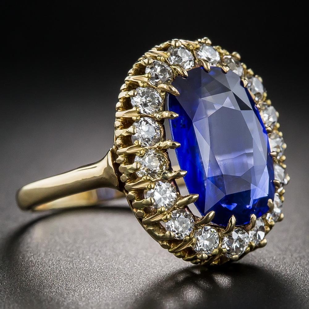 A gorgeous, richly saturated, royal-blue cushion-cut sapphire, weighing 7.68 carats, radiates from within a sparkling white diamond halo composed of 17 European-cut diamonds (totaling 1.10 carats) in this ravishing and regal antique jewel,