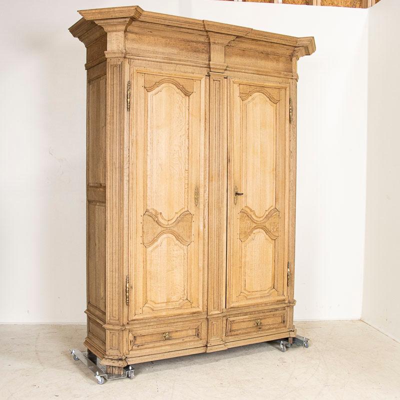 While the large size itself is impressive, it is the heavy paneling in the doors and large crown that add to the visual impact of this handsome 8' tall bleached oak armoire. Notice the long paneled doors balanced by two small lower drawers and side