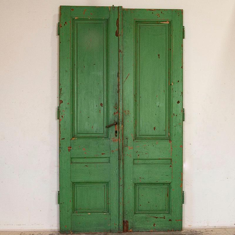 This pair of original painted doors are a fun find, complete with aged and cracked green paint and worn/distressed areas which add to the authentic vintage look. At 8.5' tall, they will make a dramatic statement with their heavy paneled details