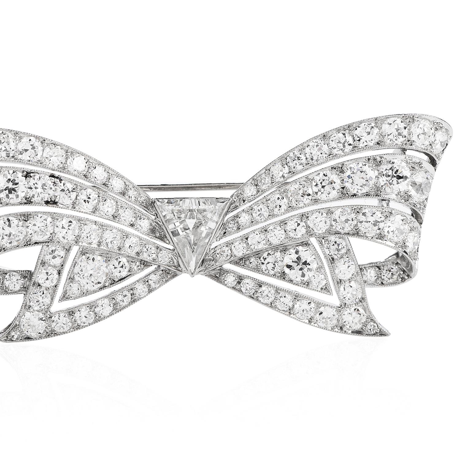 This stunning Antique 1930's diamond brooch Pin handcrafted in Platinum. This sparkling brooch pin features a bow design centered with a triangular natural diamond weighing approx. (0.85, H-I color and VS clarity) bezel-set. 
It is surrounded