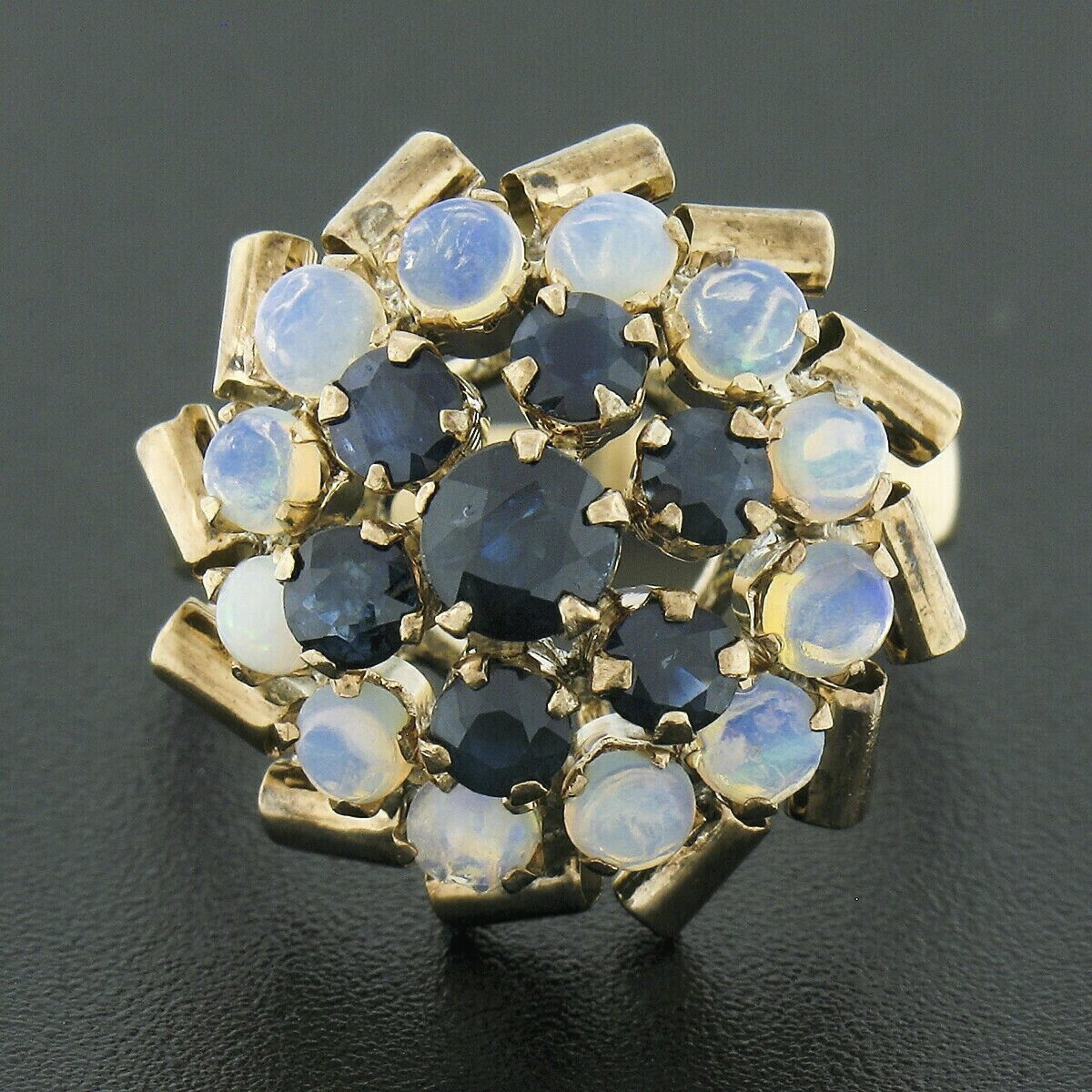 This outstanding antique cocktail ring is crafted in solid 8k yellow gold (tested) featuring a beautiful tiered design that is set with fine sapphires and opals throughout. The old round cut sapphires are neatly prong set at the top of the design,