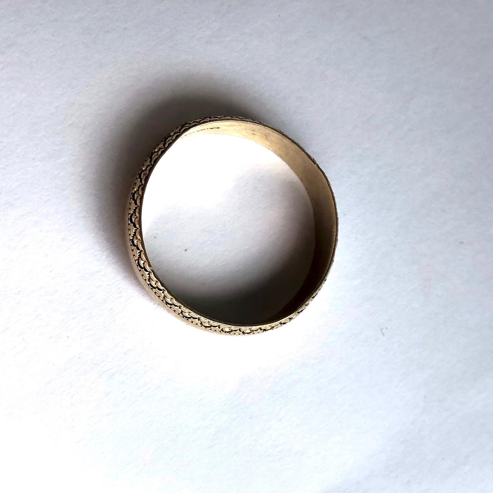 The 9ct gold band is engraved with a fancy design on both of the outer edges of the band. 

Ring Size: P or 7 1/2 
Band Width: 5mm

Weight: 2.44g