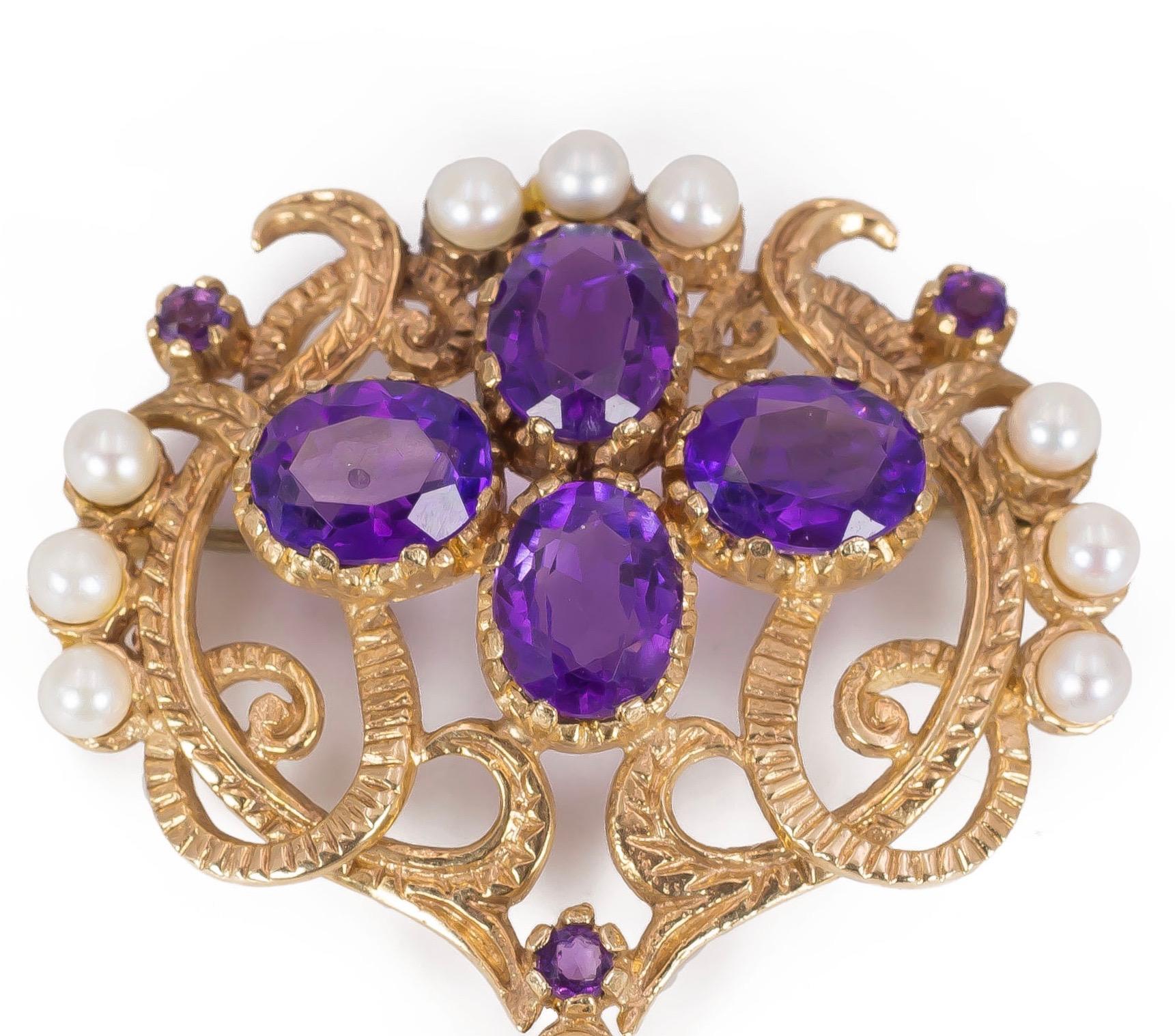 This antique brooch, dating from the early Twentieth century, features some beautiful colours: it is set with four central amethysts, two lateral ones and another one decorates an ending pendant; three outer sections are embellished with three