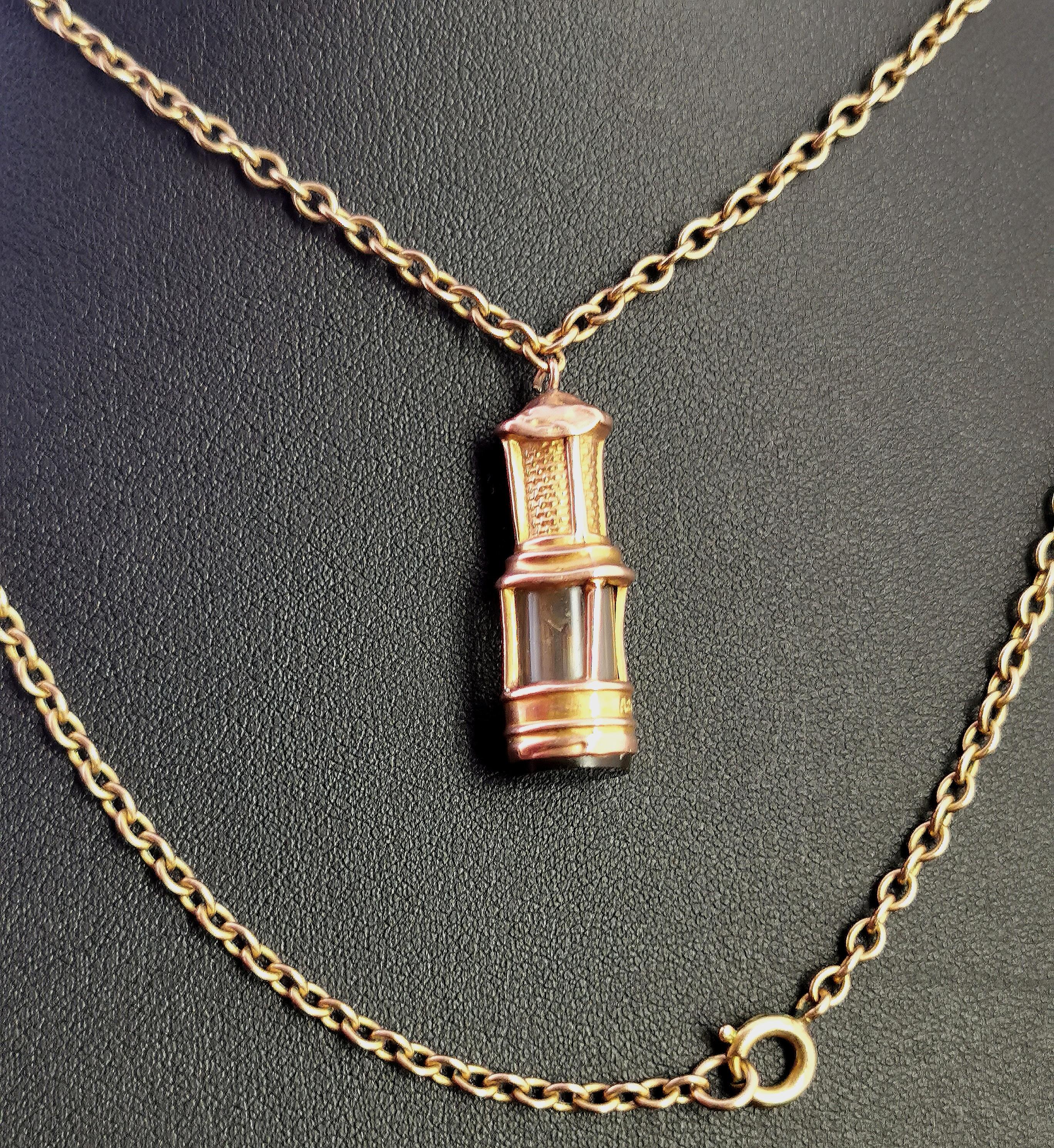 A fantastic antique gold pendant.

The pendant is modelled in 9 karat Rose and yellow gold as a miners or safety lamp / lantern, cylindrical in shape the body of the lamp is crafted from rich tones of gold with a glass centre, the base is set with a