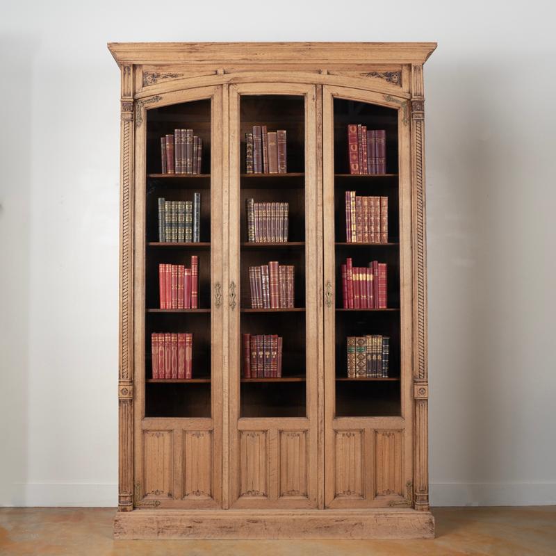 The elongated three glass doors are complimented by the carved half column details in this statuesque bookcase from France. The oak has been bleached, giving it a fresh look for today's modern home while highlighting the attractive French country