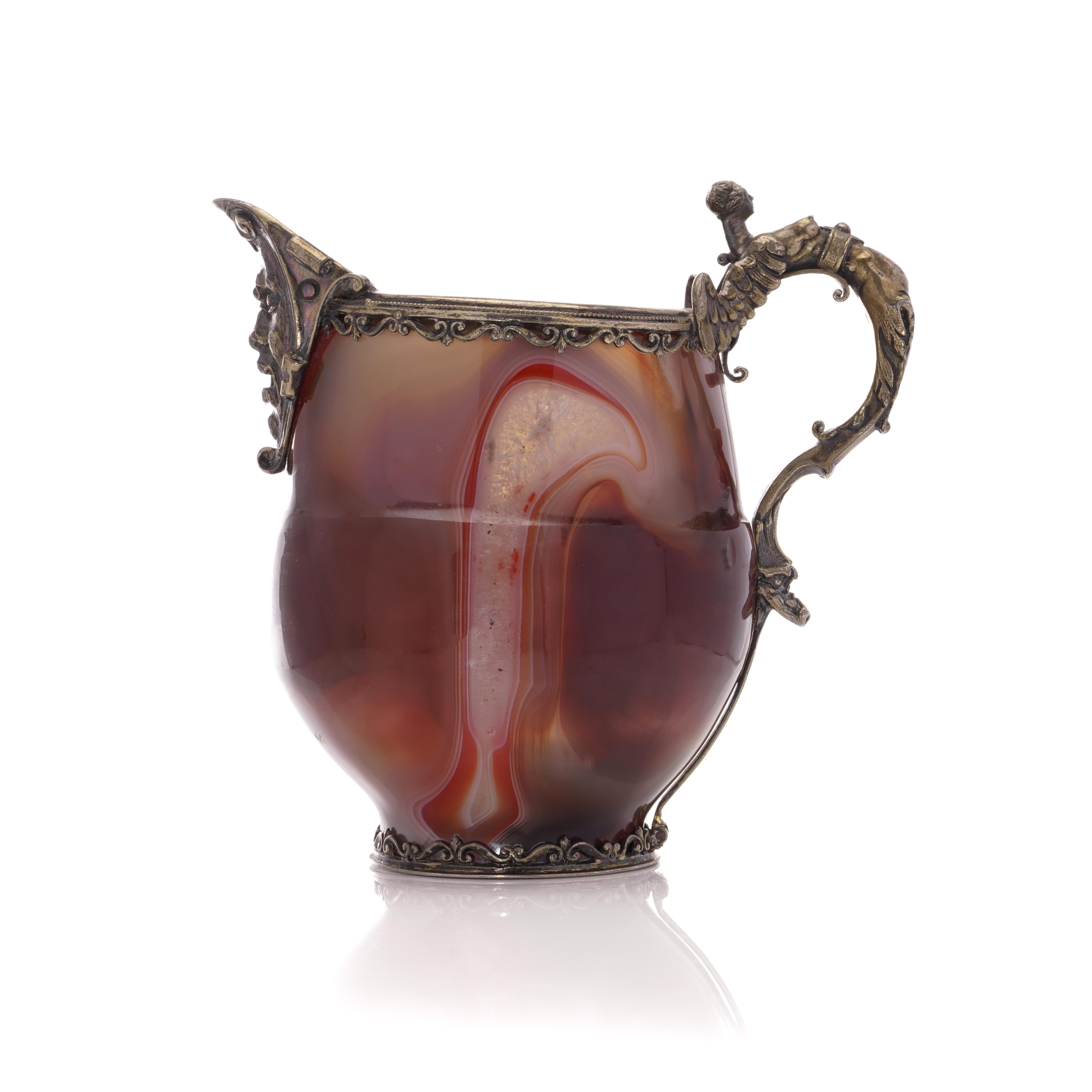 Indulge in the timeless allure of our Antique 900. Silver and Banded Agate Jug, is a masterpiece that effortlessly marries elegance and artistry. This exquisite jug is a testament to craftsmanship, featuring a highly ornate handle and rim that