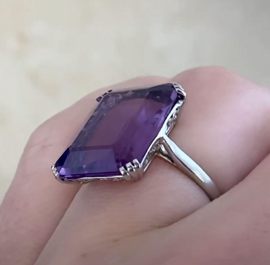 This exquisite antique ring showcases a stunning emerald-cut amethyst, weighing an impressive approx. 9.30-carats. The gemstone is securely prong-set, allowing light to pass through its rich purple hues, enhancing its brilliance and depth. A true