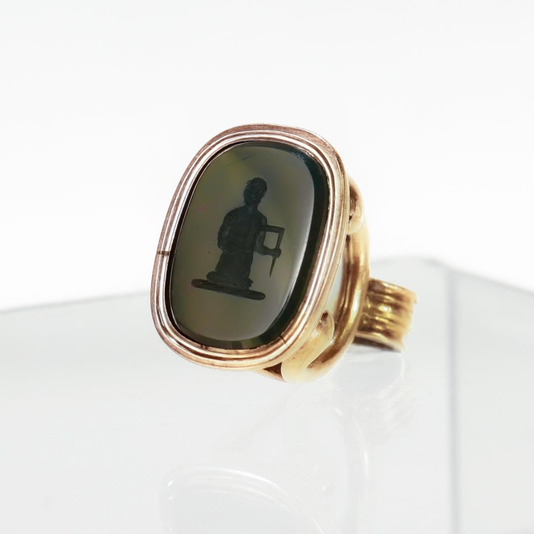 A fine antique Victorian watch fob/seal.

In 9ct gold.

Bezel-set with an intaglio carved bloodstone cabochon depicting a man holding a staple-like tool.

Simply a wonderful watch fob/seal!

Date:
19th Century

Condition Details:
The cabochon is