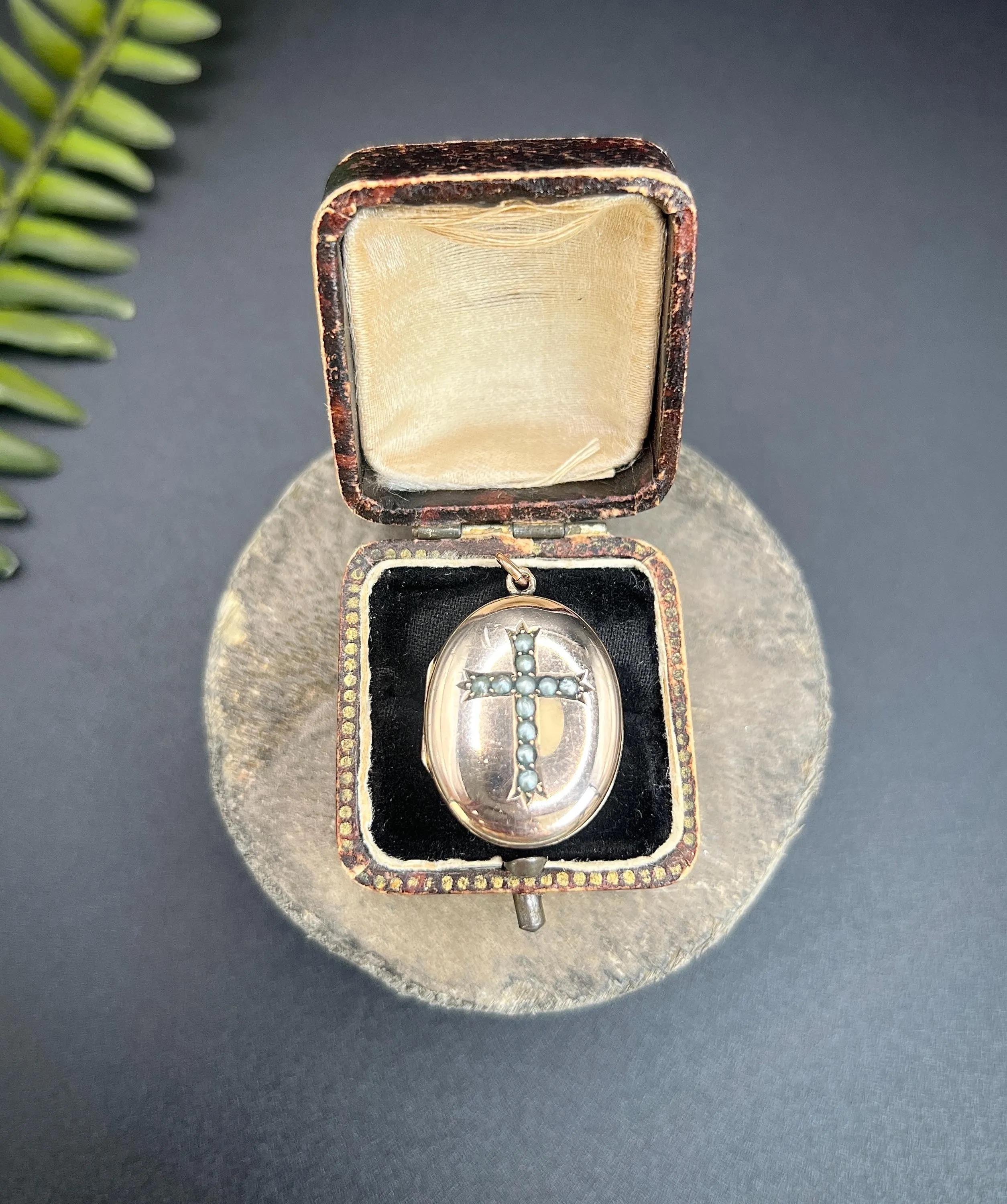 Antique Oval Locket 

9ct Gold 

Circa 1910

*THE CHAIN IS SOLD SEPARATELY 

This stunning 9ct gold locket, hailing from the Edwardian era, features an elegantly oval shape adorned with a beautifully crafted seed pearl set cross on the front. Its