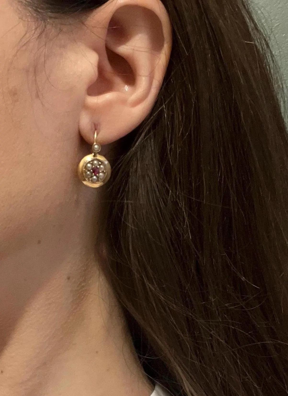 Boucles d'oreilles circulaires anciennes en rubis et perles 

Or 9 carats

Circa 1910

Cette paire vintage présente un rubis central entouré de petites perles blanches en forme de grappe circulaire. La monture en or ajoute de la chaleur et du