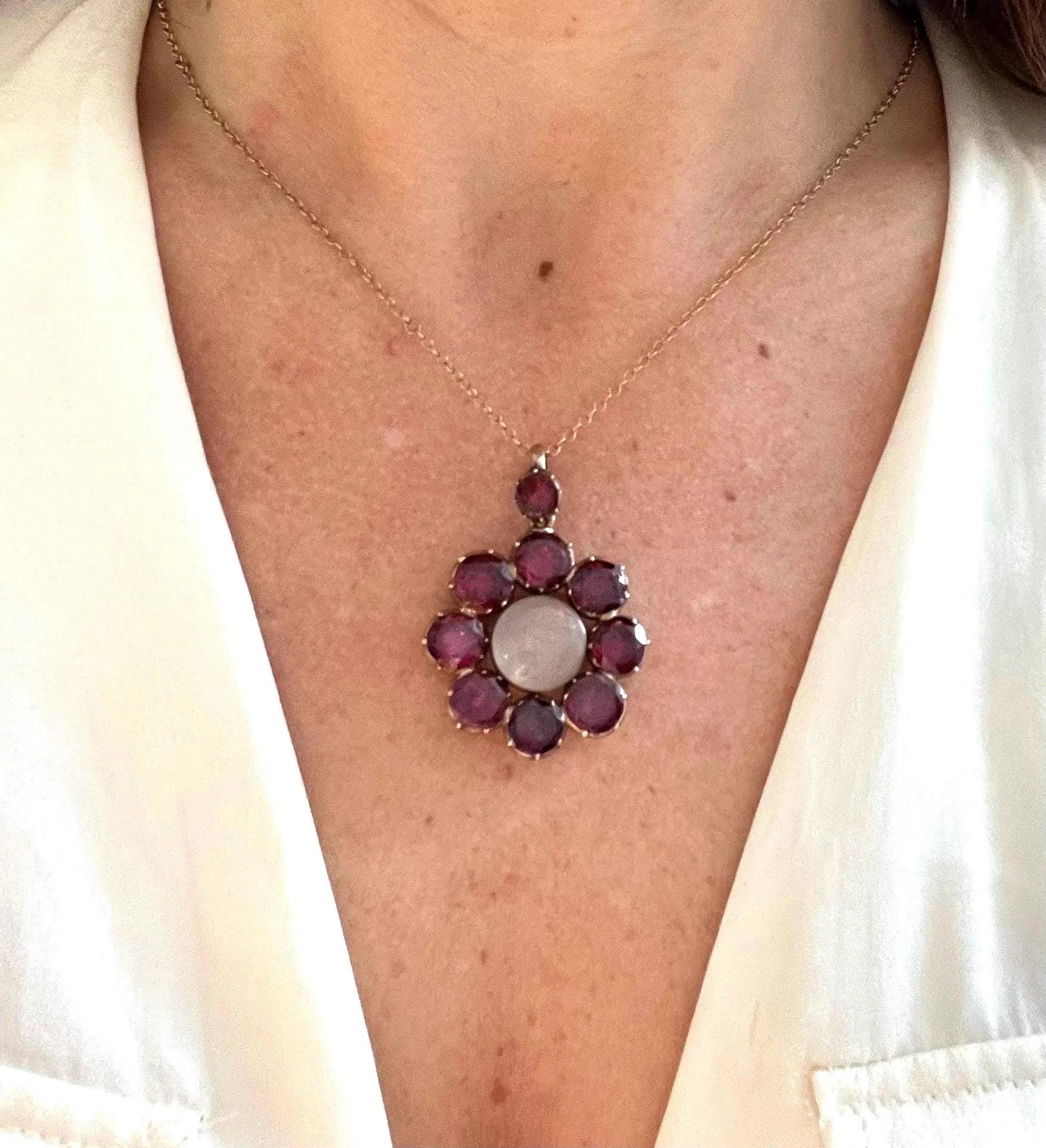 Antico medaglione georgiano a forma di fiore con granato

Oro 9ct

Circa 1820

 La catena d'oro è venduta separatamente.

Un radioso grappolo di granati cremisi profondi circonda un segreto nascosto: questo antico ciondolo nasconde un medaglione a