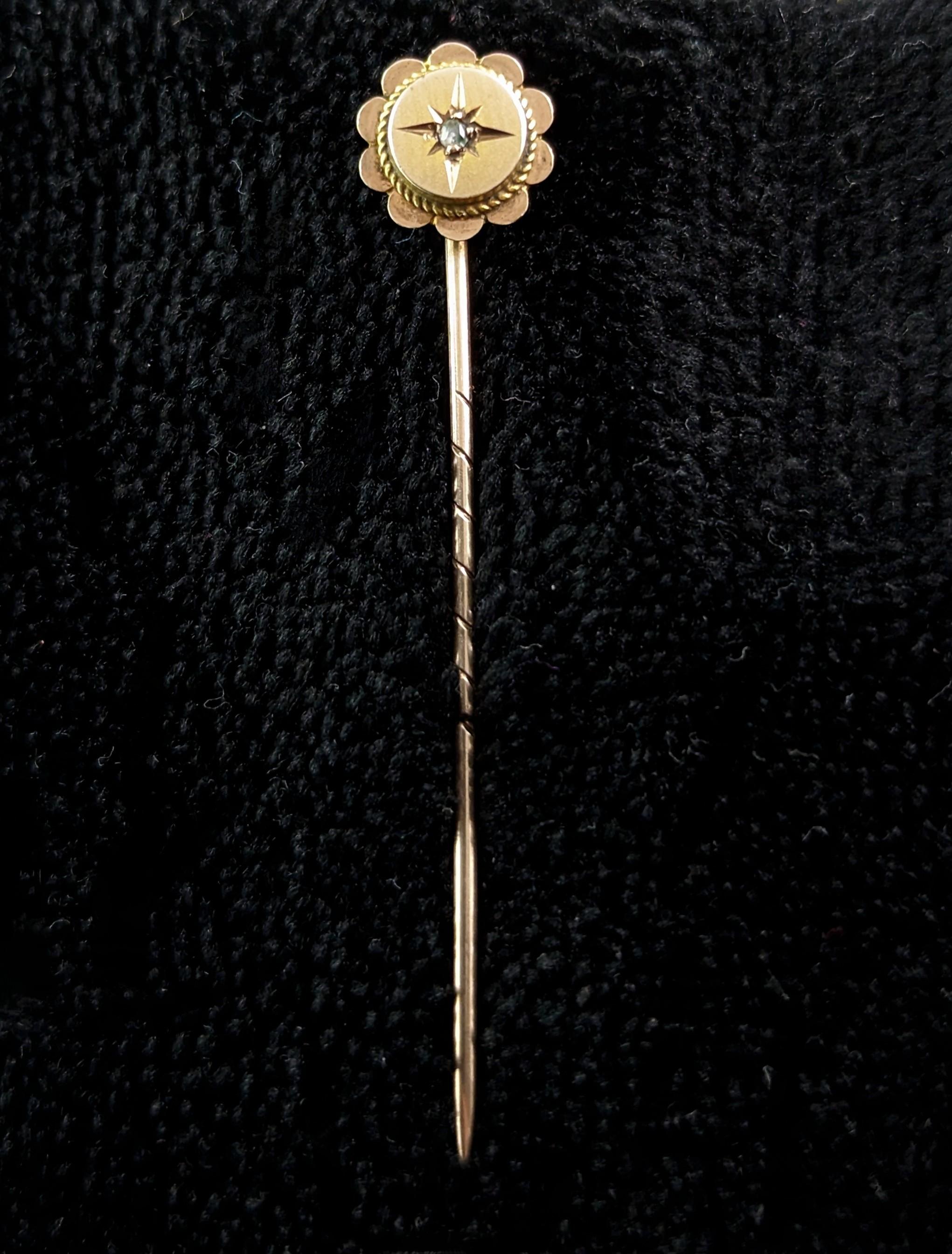 An attractive antique 9ct gold and diamond stick pin.

A 9ct yellow gold stick pin with an almost floral shaped terminal set with a single diamond chip in a gypsy style star setting.

The stick pin also known as a tie or cravat pin started out its
