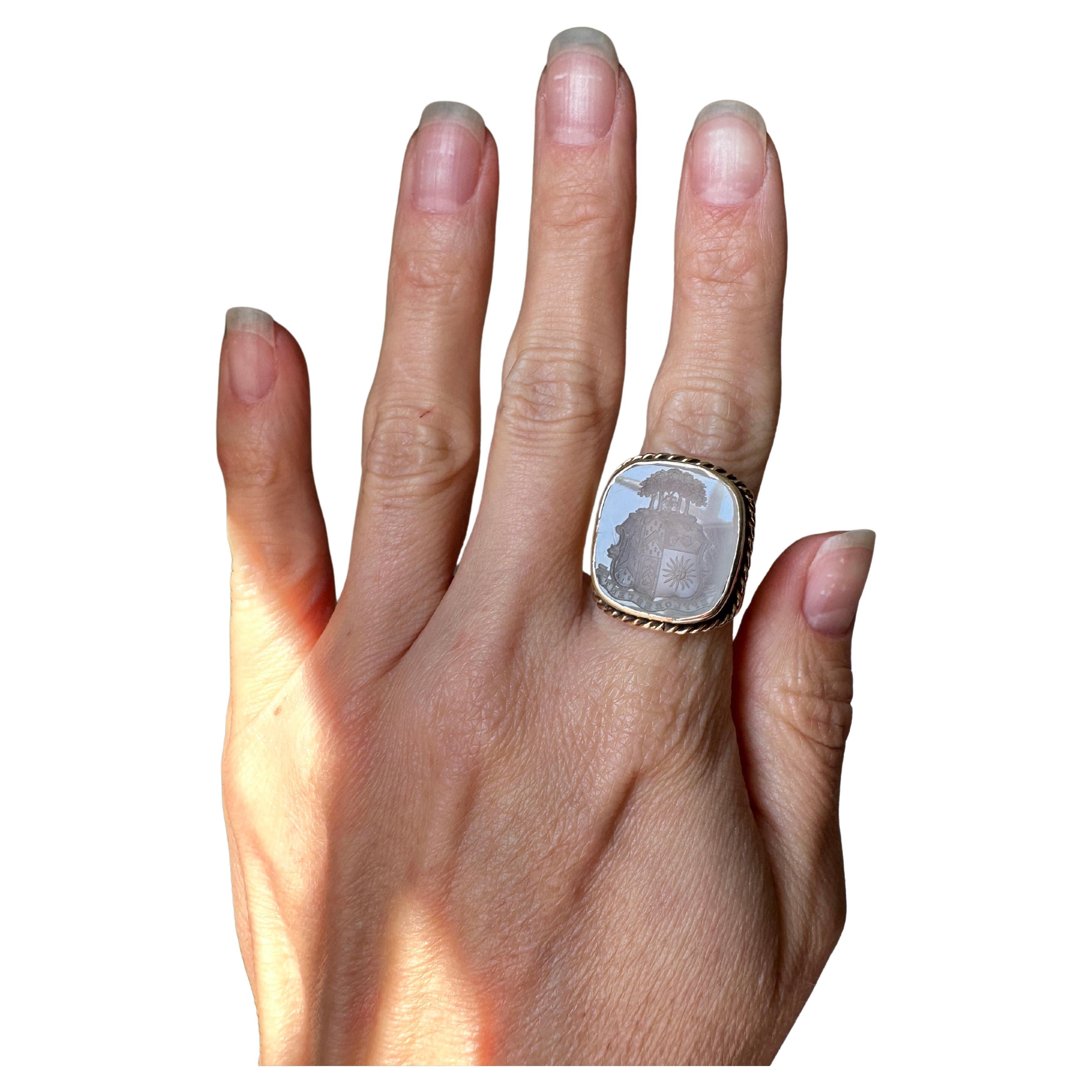 Originally a Victorian era fob converted in antiquity to a ring modeled in 15k gold, a luminous white chalcedony intaglio displays a finely hand-engraved seal filled with captivating details such as a lush thicket of tres, pair of hands, flowers,