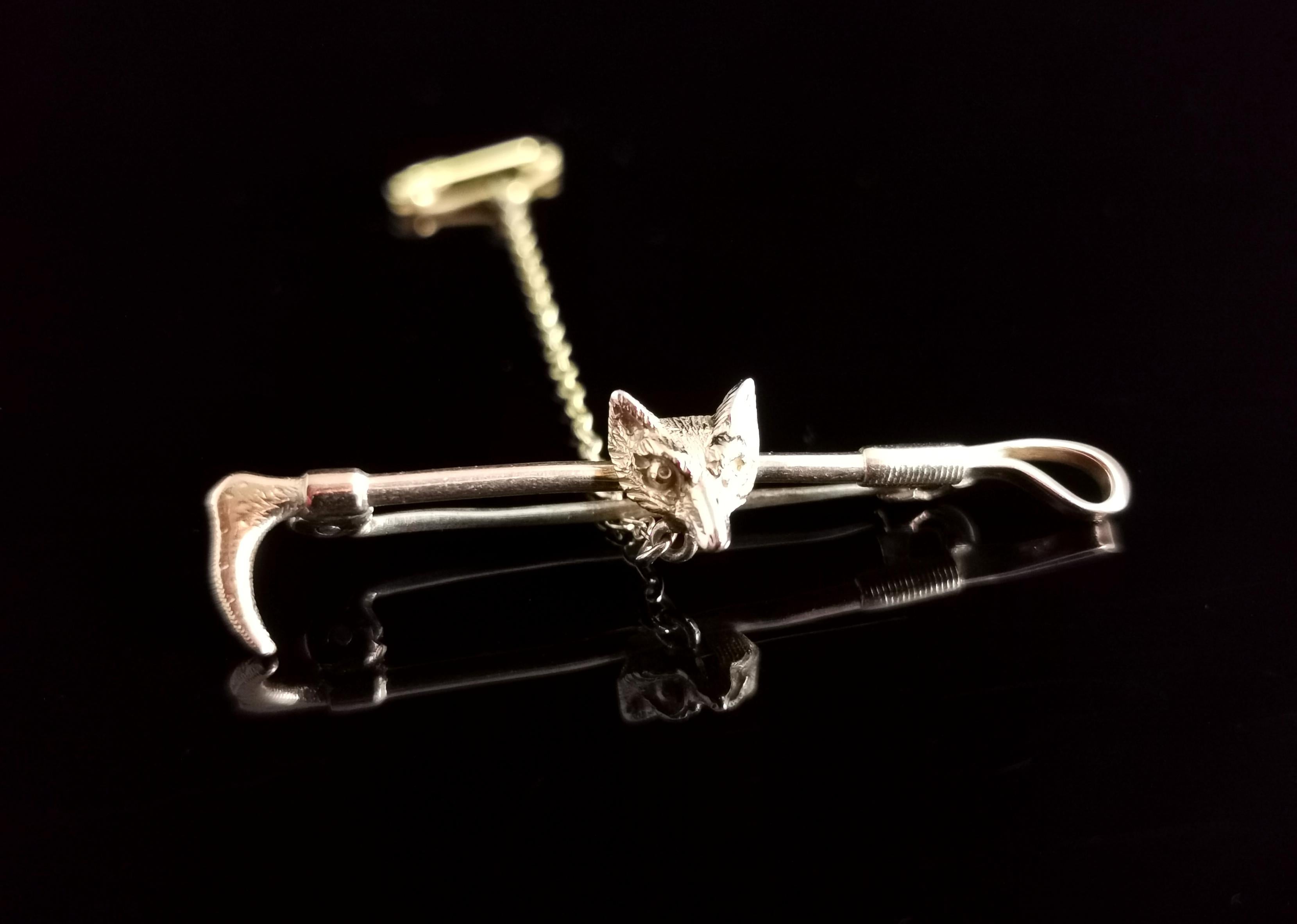 A well detailed antique 9ct gold fox and riding crop brooch or pin.

It has subtle bi colour gold highlights with some yellow and some rosey gold areas.

The brooch features a fox head to the centre which is realistically textured, mounted onto a