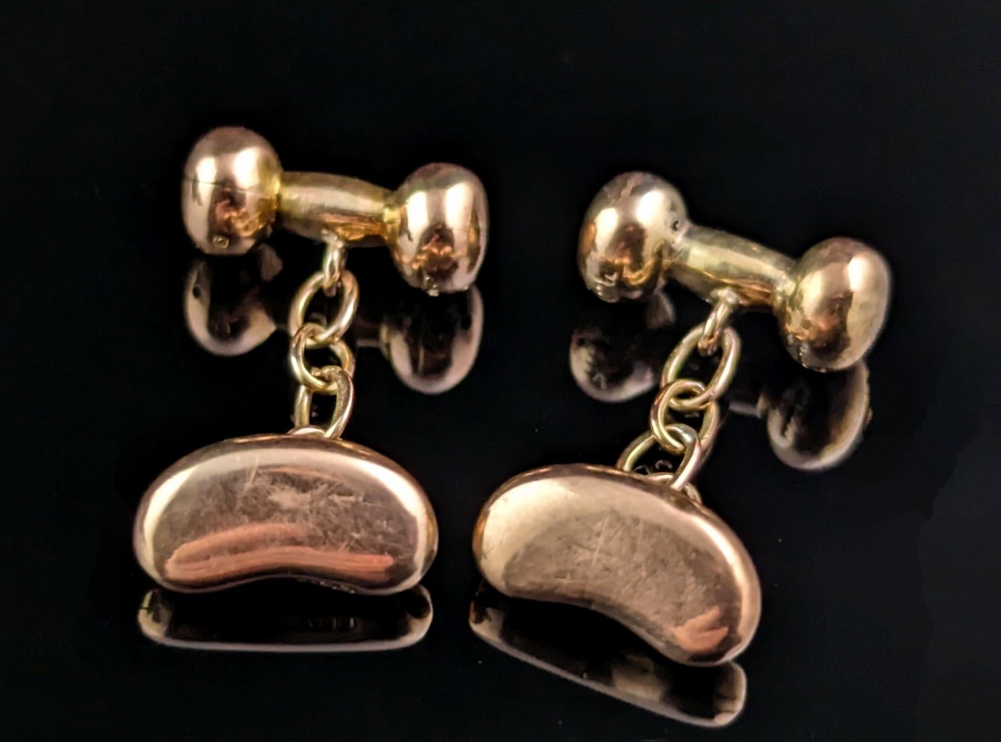 A fantastic pair of antique Edwardian era 9ct Rose gold lucky bean cufflinks.

They feature a modelled rose gold lucky bean to one end and are attached to a ball and barbell anchor with a short gold chain.

The cufflinks are stamped and marked in