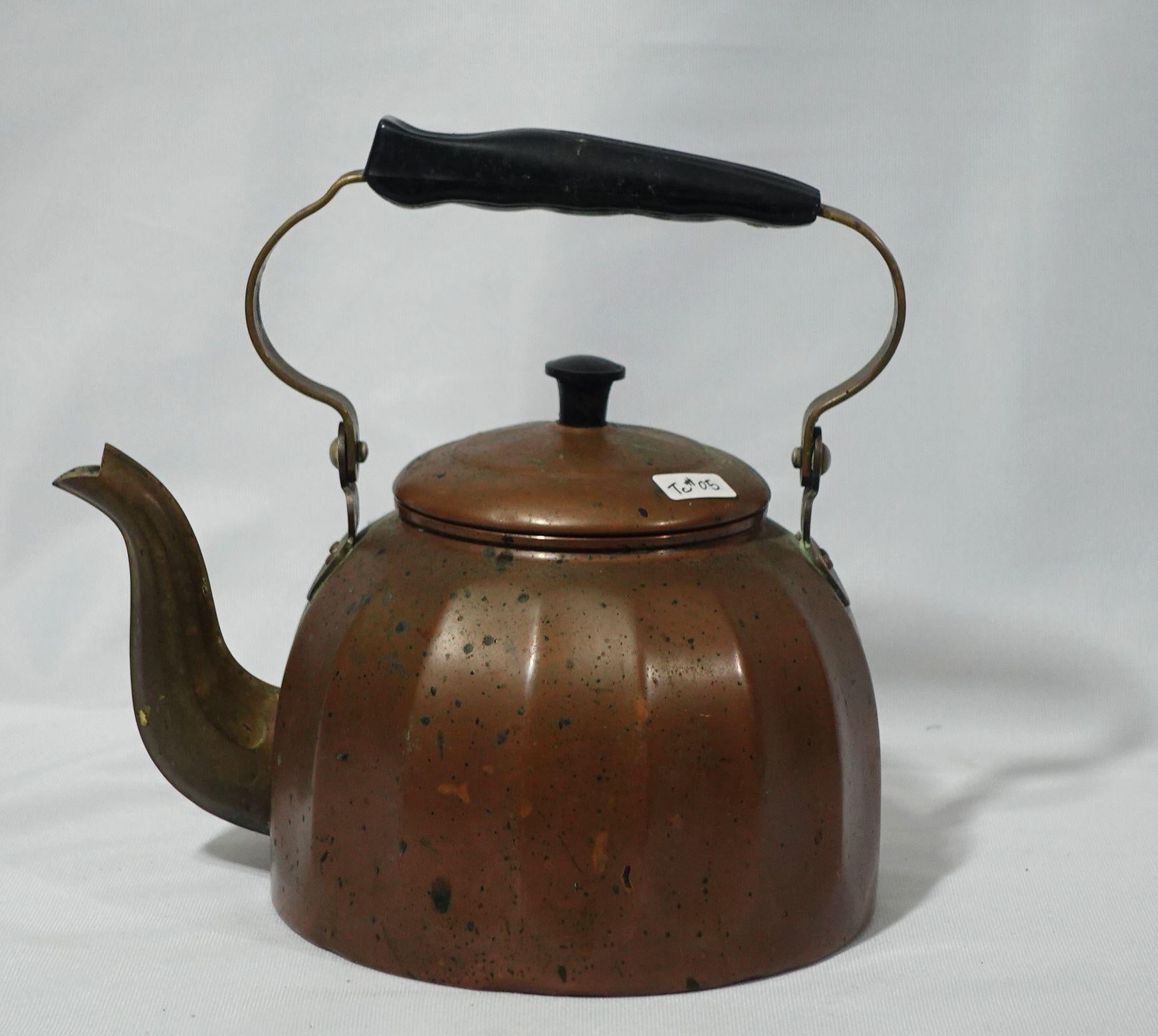 Hand-hammered-shaped copper tea kettle with a wood handle marked on the bottom 