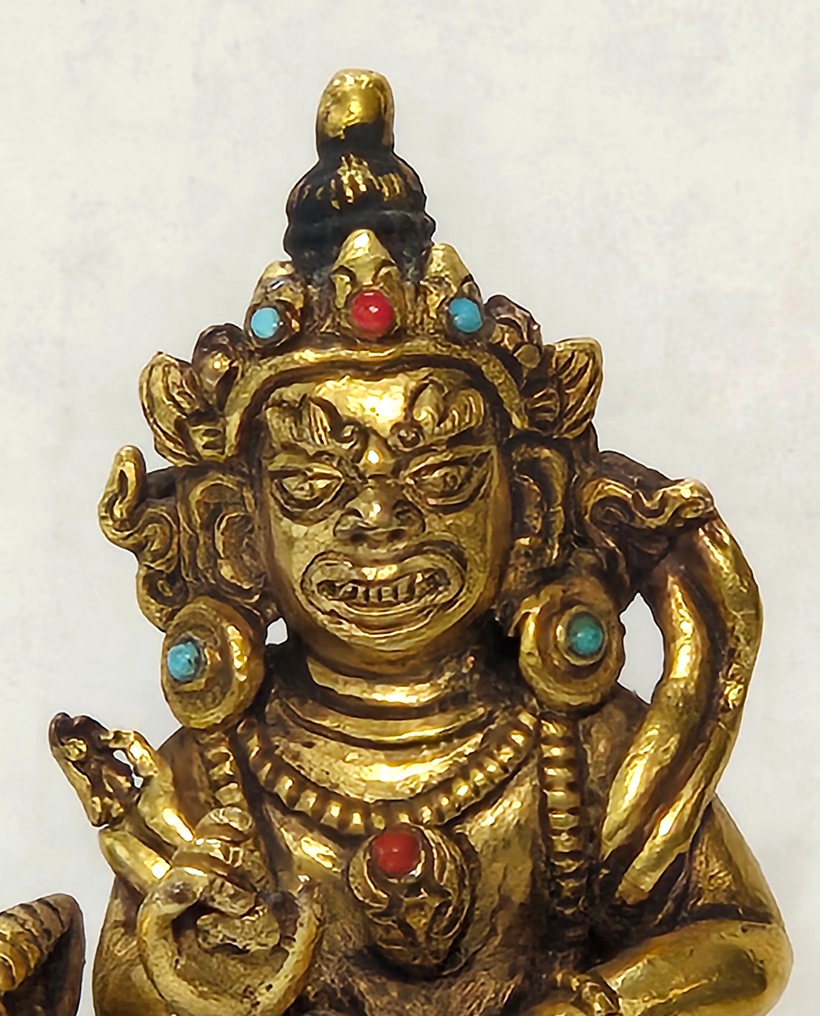 A SINO-TIBETAN GILT BRONZE FIGURE  ON HARDWOOD STAND, heavily composing a finely sculpted gilt bronze figure of a deity resting on a horse with chased detailing and turquoise and coral embellishments resting on a wood platform, 18th century. The