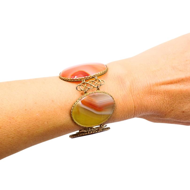 Esta pulsera antigua de A & J. Smith de Aberdeen muestra la elegancia intemporal de la joyería escocesa de finales de la época victoriana. Realizado en oro de 9 quilates, presenta cinco grandes cabujones ovalados de ágata multicolor, cada uno con un