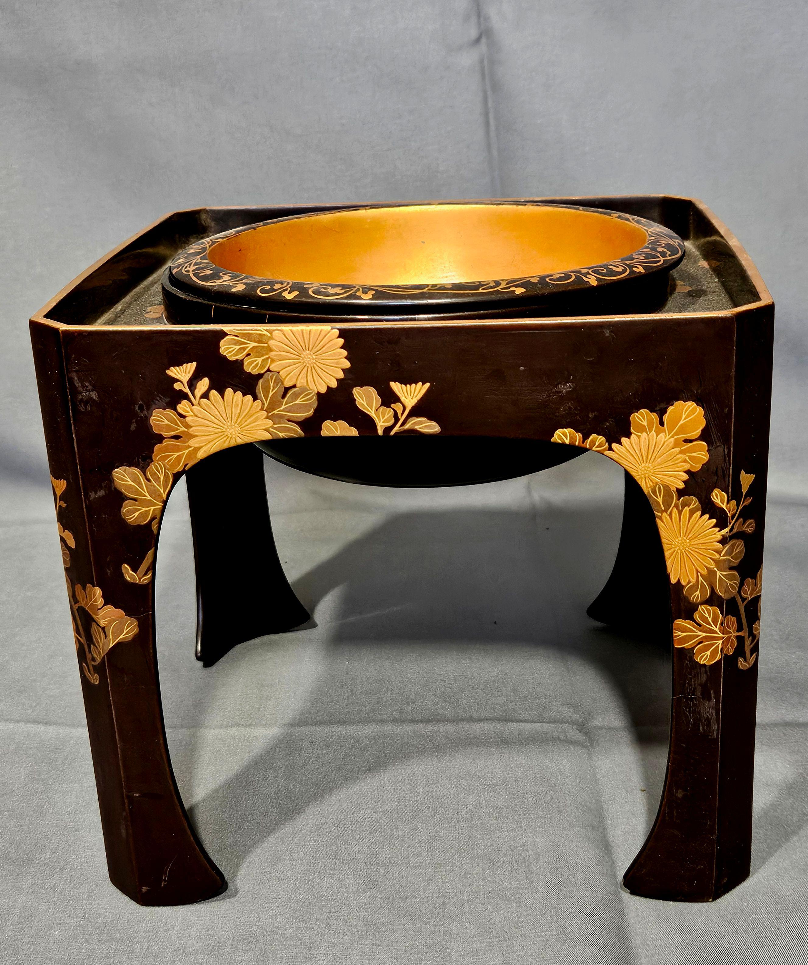 Cuenco de laca negra en soporte encajado, con decoración floral y enredadera dorada en relieve, 6 3/4