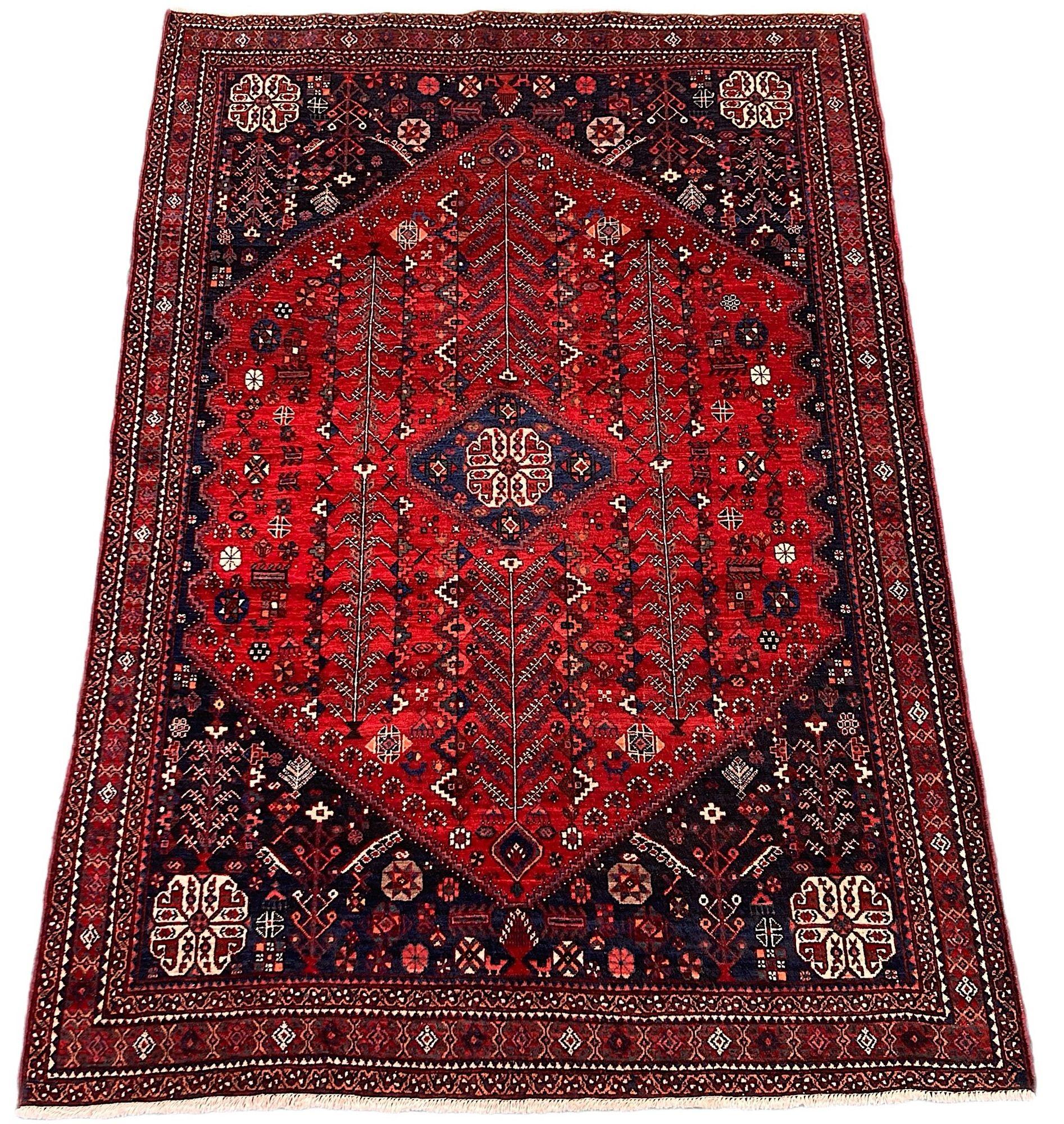A beautiful antique Abadeh rug, hand woven circa 1920. The design features a small geometrical medallion on a rich red field of stylised flowers and vines surrounded by a deep indigo border. Finely woven with soft, velvety wool and lovely secondary