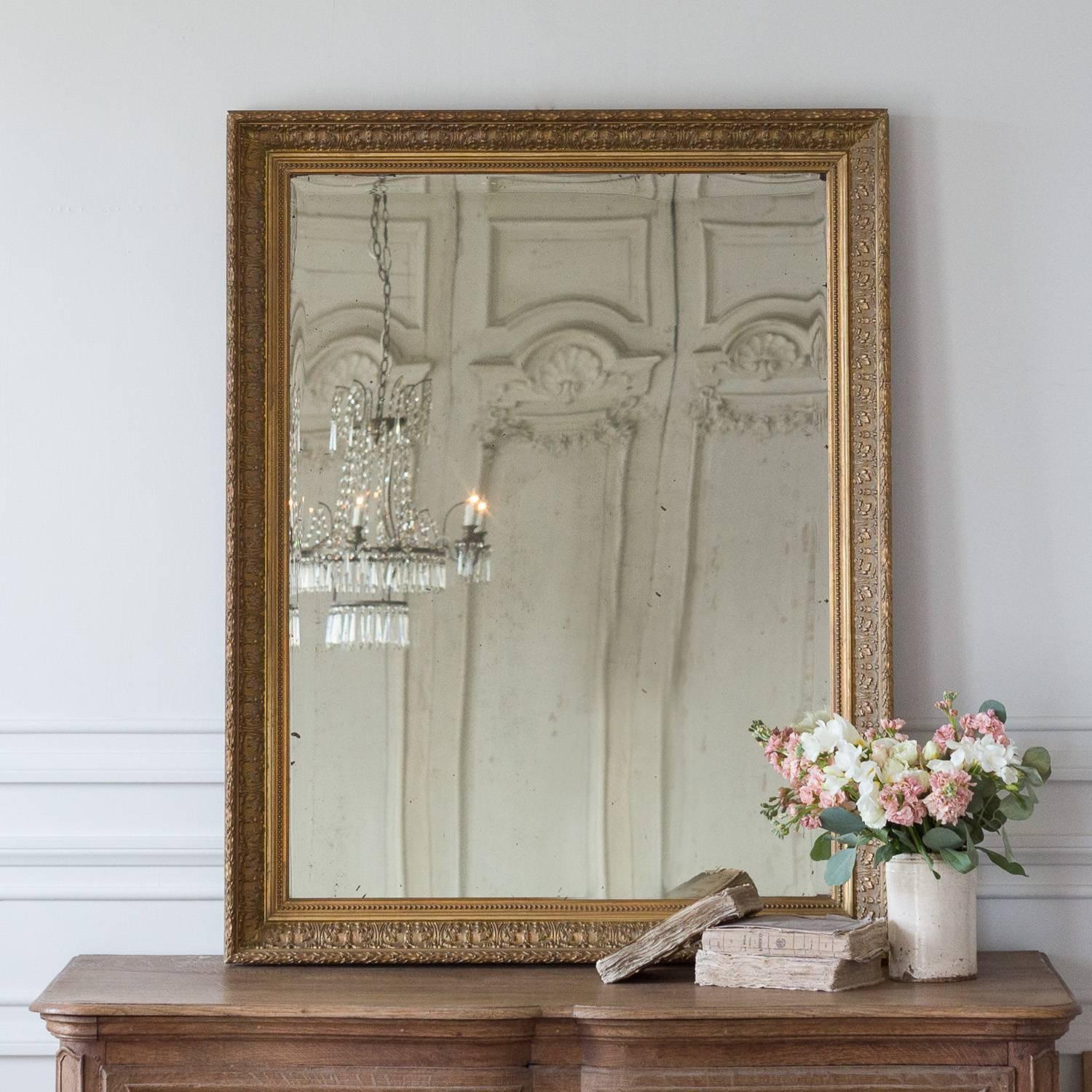 This simple framed antique mirror with beveled glass has a thick frame with repeating floral and leaf motif. Small beads surround the inner frame. The glass has yellowed somewhat. Sweet addition to an entryway or hallway.