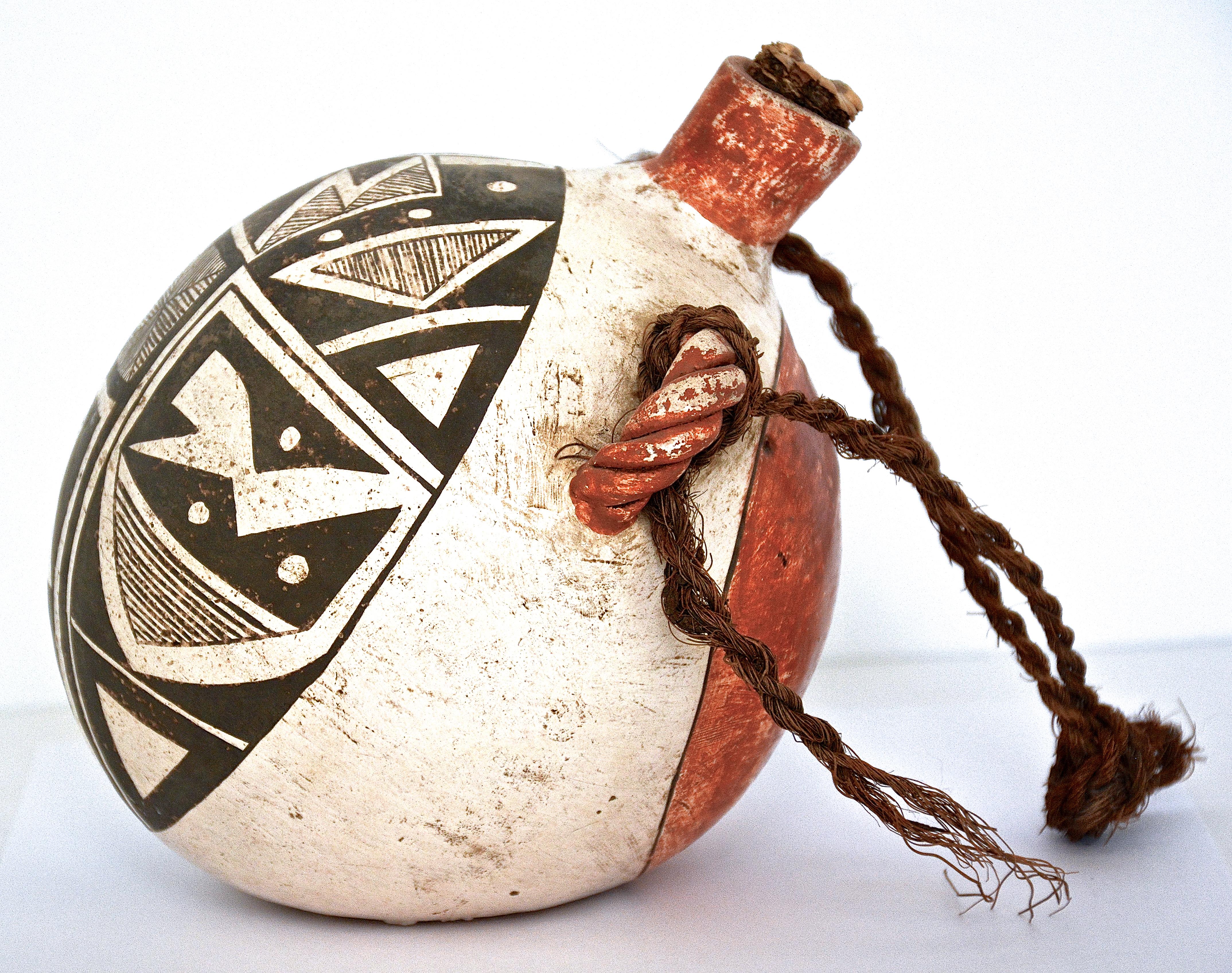 Pottery Canteen
Acoma
1900
6 inches Height x 5.50 inches Diameter.
Clay, mineral pigments, twined fiber cordage, corn cob. 

A wonderful example of an antique polychrome Acoma Pueblo Globular Pottery Canteen circa 1900, with geometric designs. 

In