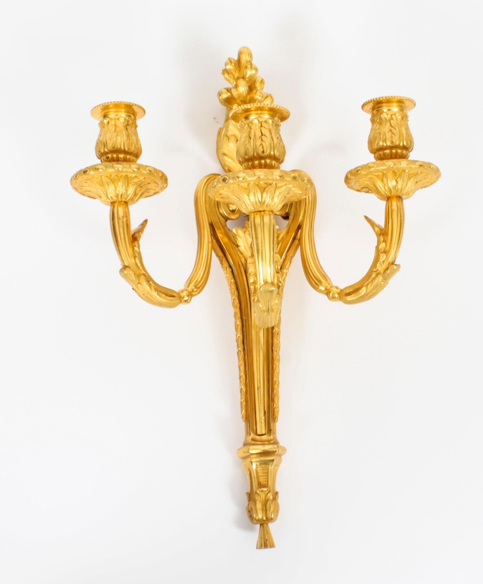 This is a stunning pair of Adam Revival antique gilded ormolu triple branch wall lights, dating from the late 19th century.
 
Each wall light has a tapering body, supporting a spiral twist and acanthus cast candelearm terminating in gadrooned