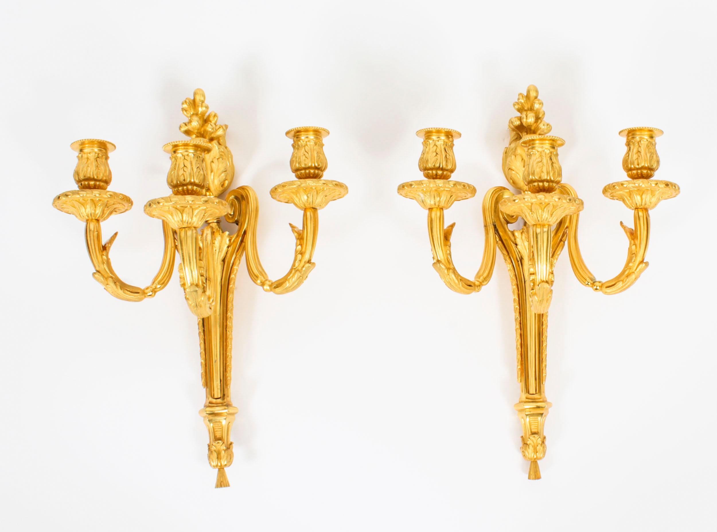 This is a stunning pair of Adam Revival antique gilded ormolu triple branch candle wall lights, dating from the Circa 1840.

Each wall light has a tapering body, supporting a spiral twist and acanthus cast candelearm terminating in gadrooned sockets
