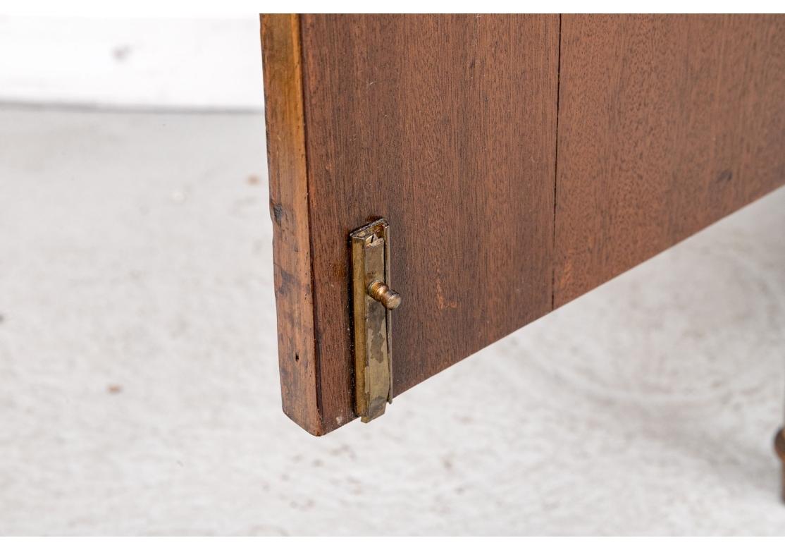 Un armario con bandas de madera en tono miel finamente pintado al estilo clásico de Adam. La encimera tiene esquinas de galleta y está montada sobre el mueble con un solo cajón de friso y puertas dobles. Se abren a un espacio de almacenamiento con