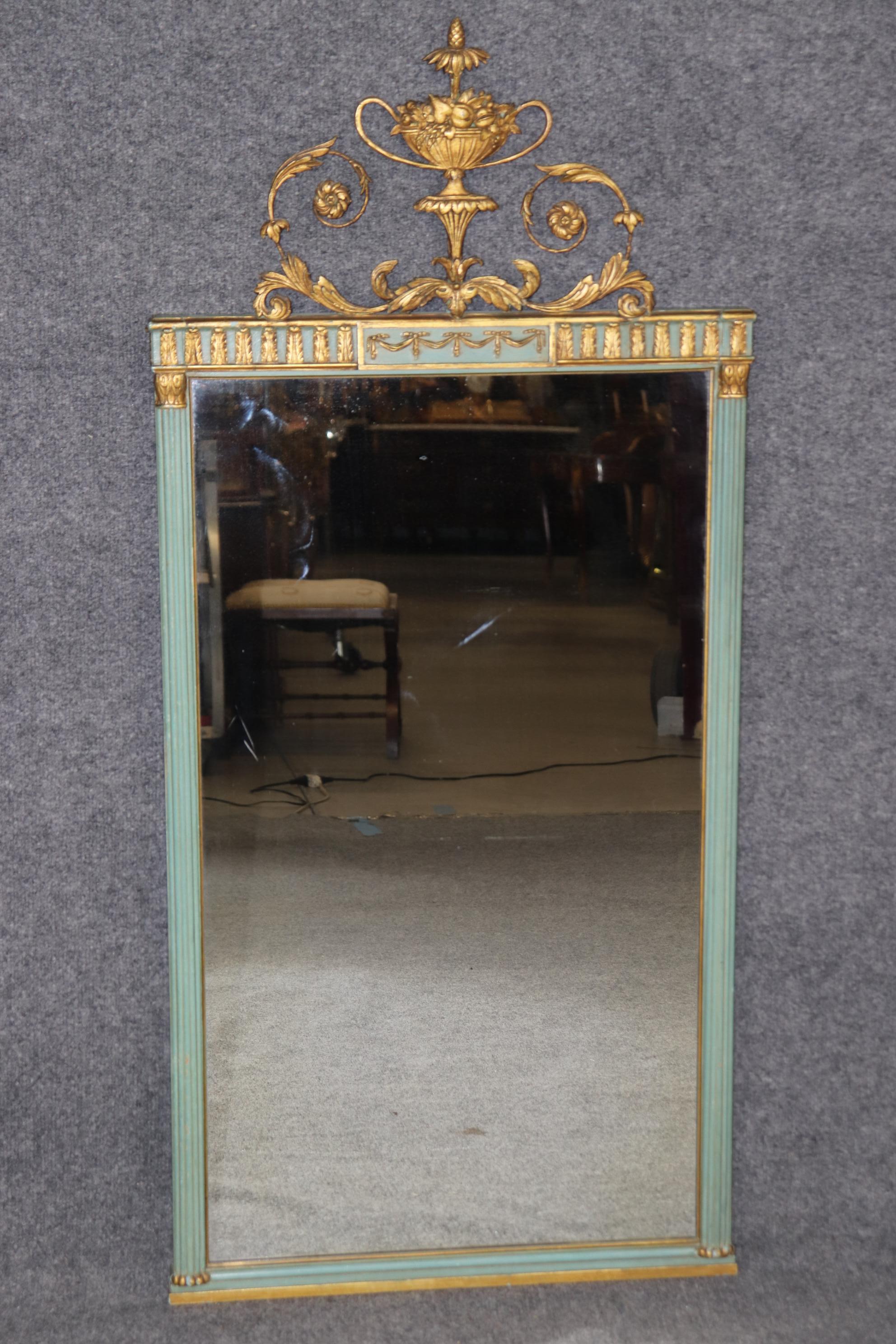 Dimensions - H : 46 1/2 in W : 21 1/2 in D : 1 3/4 in 

Un époustouflant miroir ancien sculpté de style Adams, délicieusement décoré à la peinture bleue et orné de touches dorées, incarnant l'élégance raffinée du design néoclassique du XVIIIe