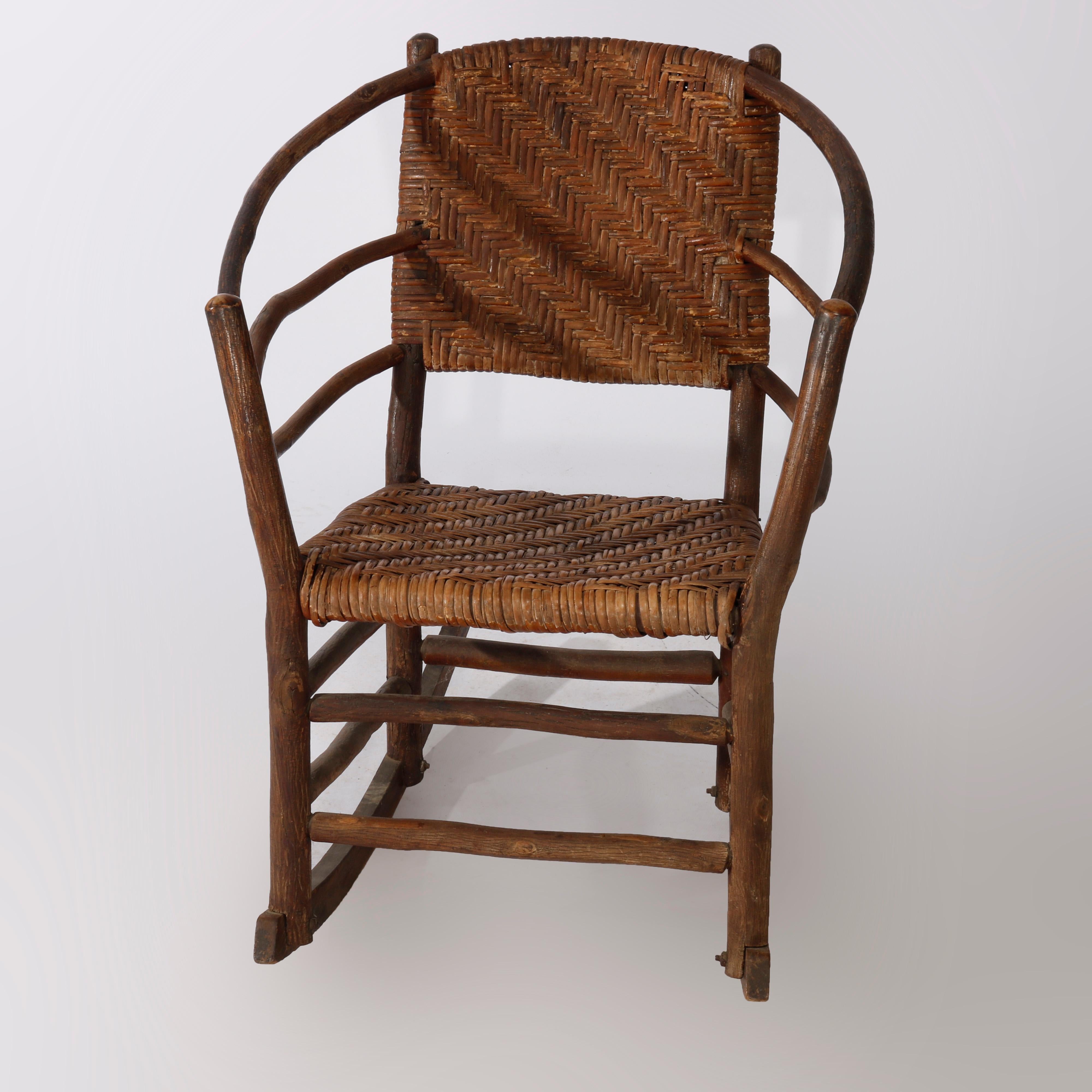 An antique Adirondack rocking chair by Old Hickory offers stick construction in barrel back form with triple stick arms and reeded seat and back, maker signed, c1910

Measures - 32.75'' H X 25'' W X 27'' D.
 