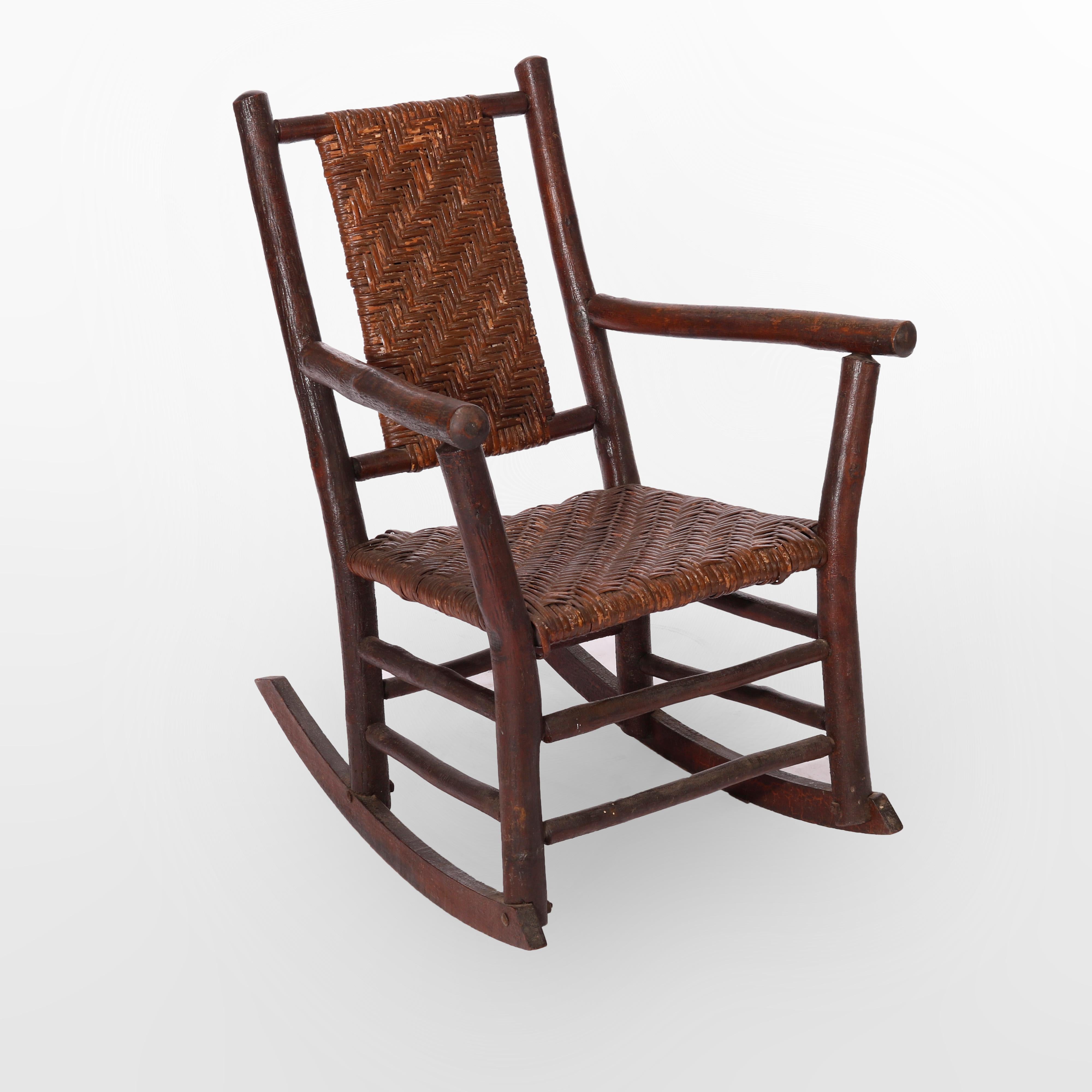 An antique Adirondack rocking chair by Old Hickory offers stick construction in form with reeded seat and back, maker signed, c 1910

Measures - 34.5''H x 25''W x 30''D.