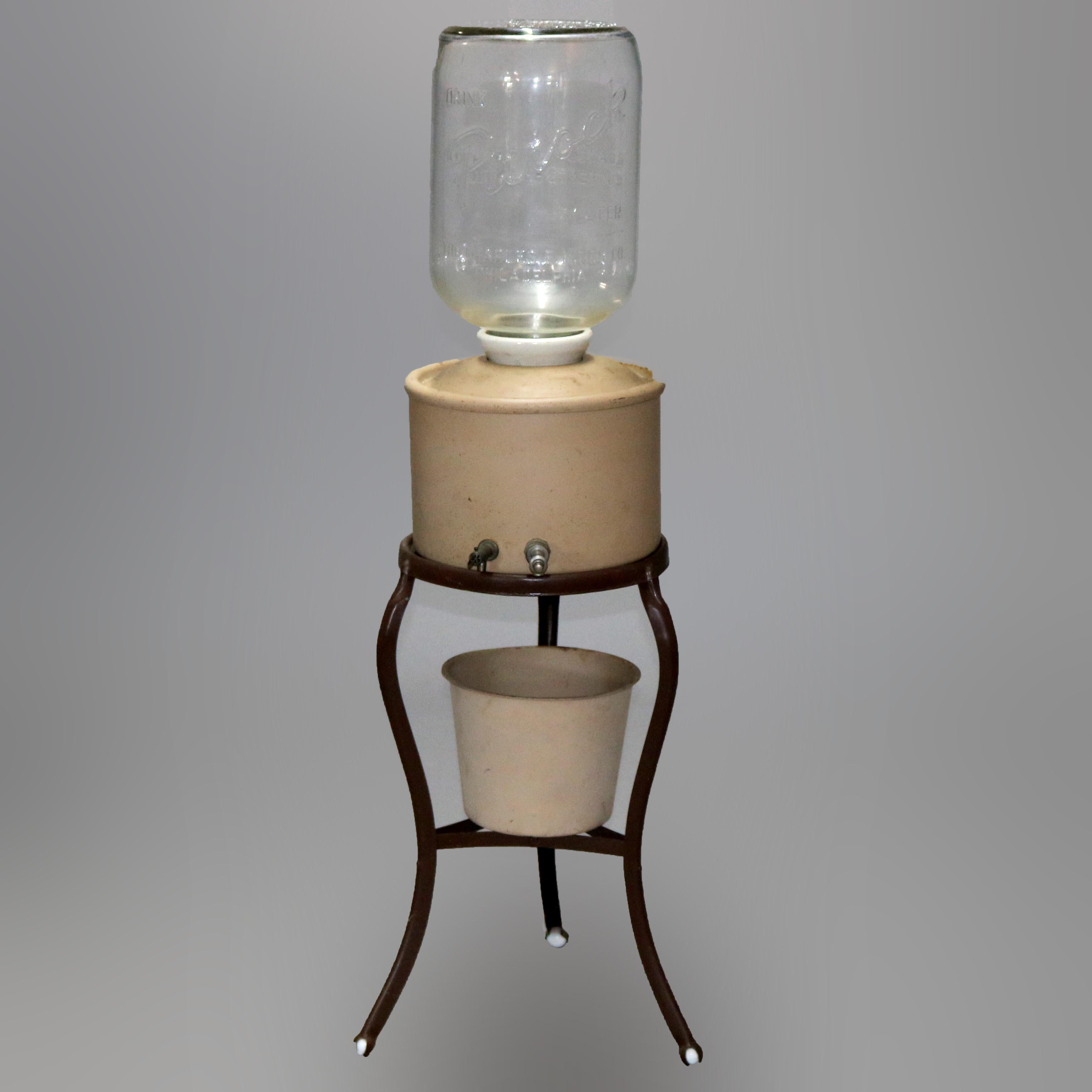 An antique Purock water cooler offers metal dispensing unit on iron base with lower vessel and glass jug having embossed Purock, c1930.

Measures: 19.38