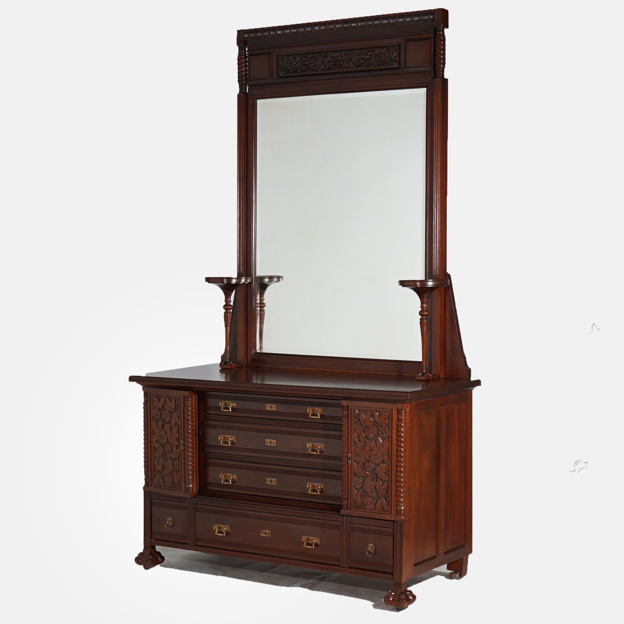 An antique Aesthetic Movement dresser offer mahogany construction with mirror having foliate carved crest and flanking candle stands over chest with central drawer tower having flanking cabinets over single long drawer, raised on stylized paw feet,