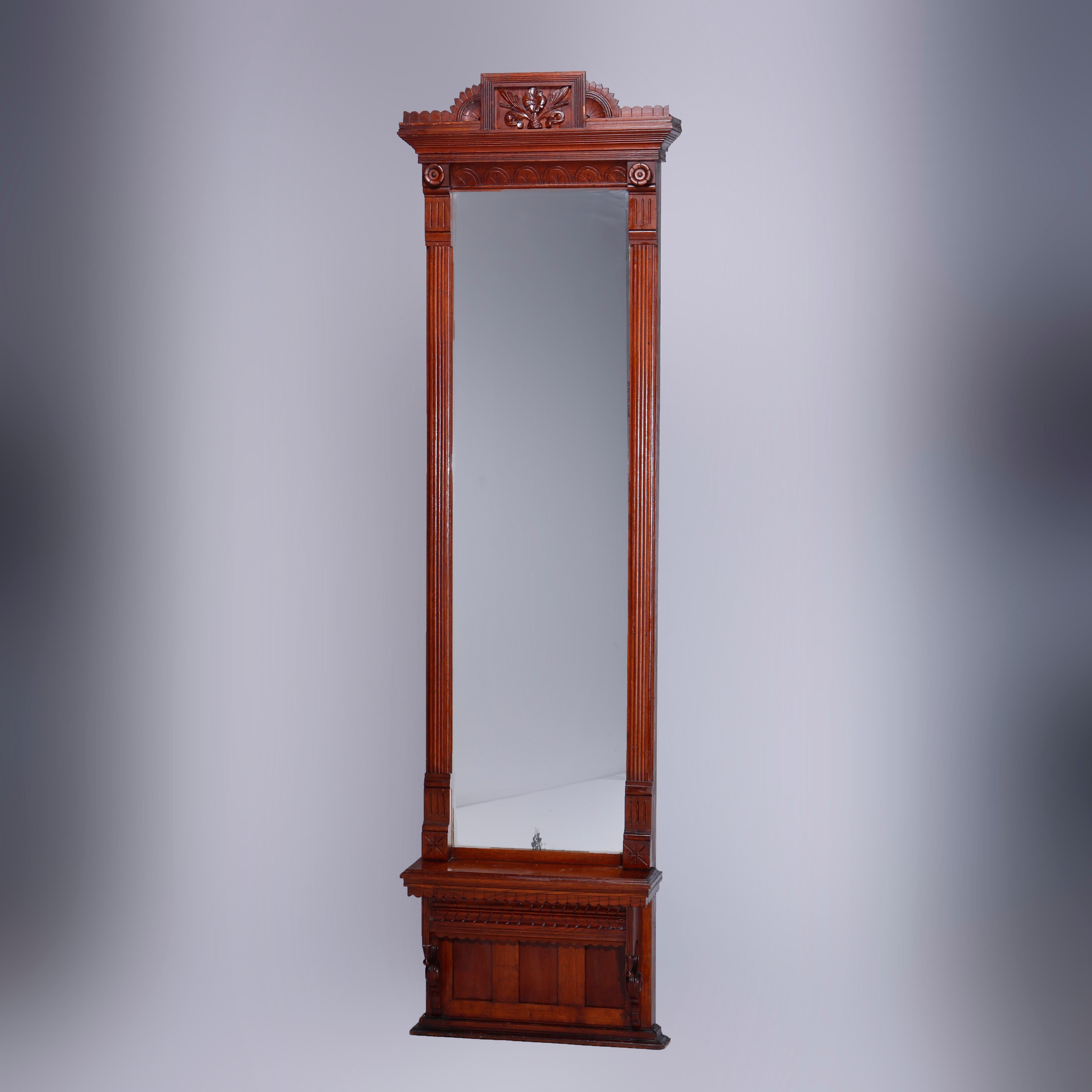 An antique Aesthetic Eastlake pier mirror offers oak construction with carve foliate crest having flanking stylized sunburst elements reeded frame housing mirror surmounting paneled base with shaped skirt and drop finials, incised decoration