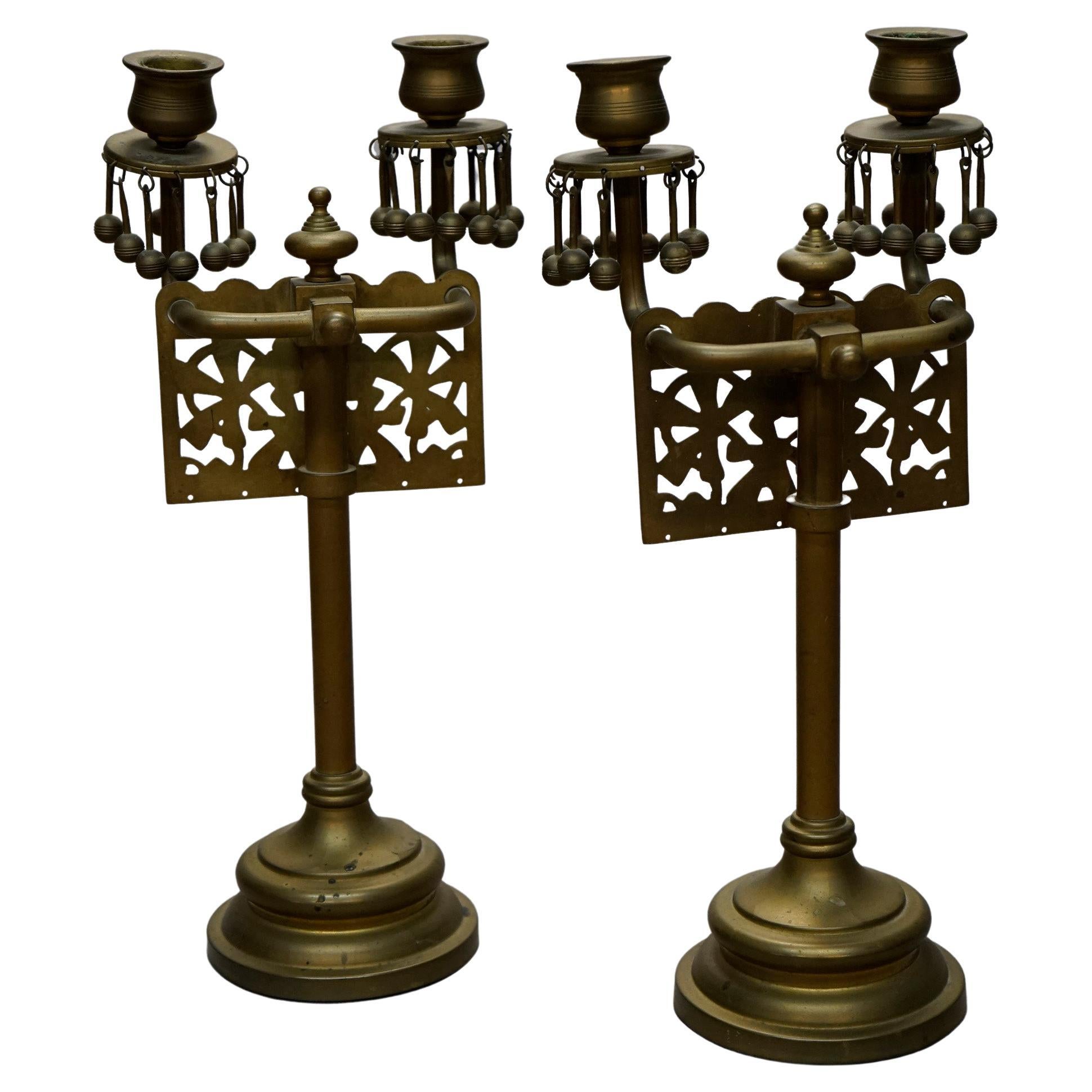 An antique set of Aesthetic Movement candelabra offer brass construction with pierced panel of stylized flowers and two candle sockets each, raised on column with stepped base, c1880

Measures- 14''H x 6.25''W x 5''D.

Catalogue Note: Ask about