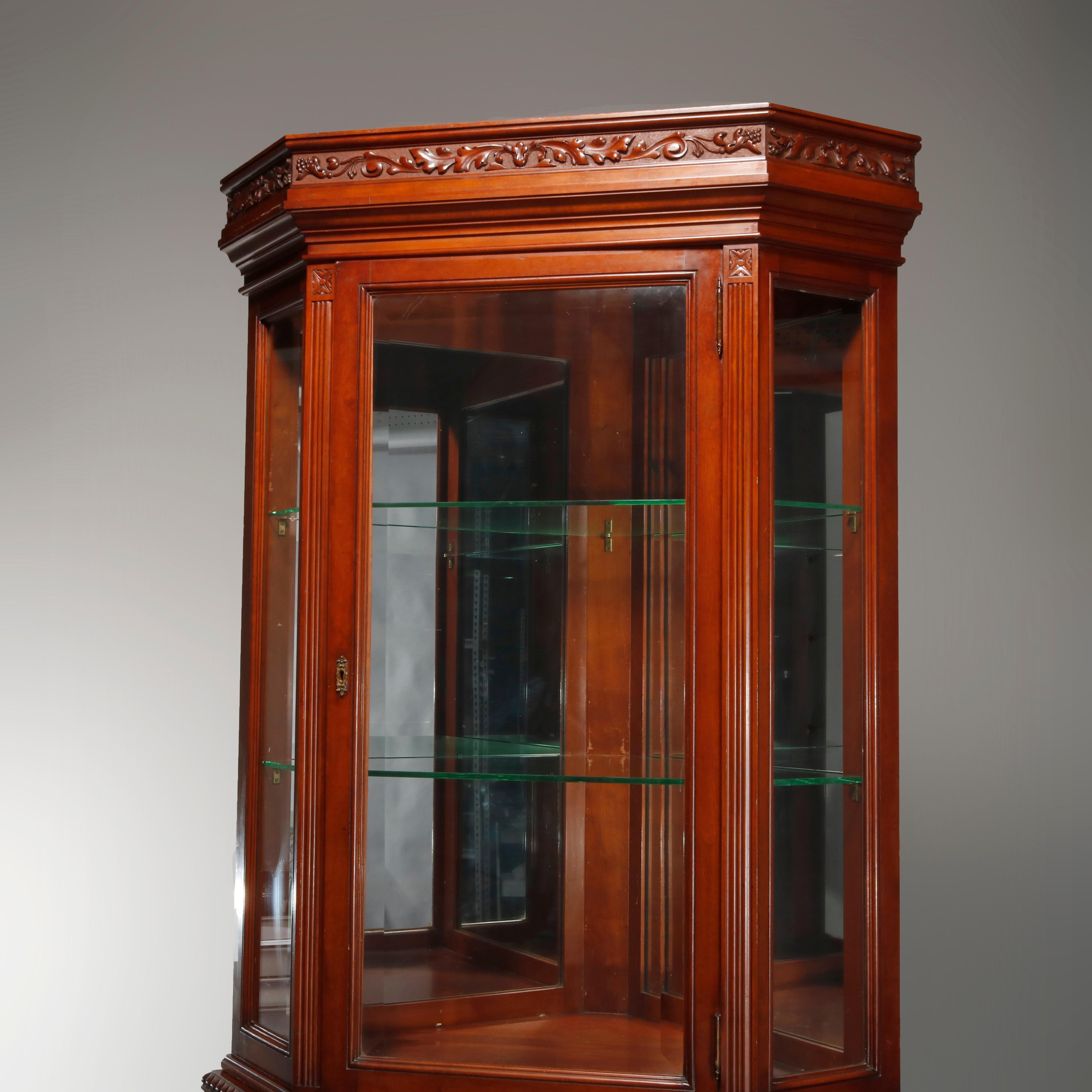 An antique aesthetic movement corner cabinet offers cherry construction in faceted form with carved foliate frieze surmounting cast with single beveled glass door opening to shelved and mirrored interior over paneled cabinet with gadroon trim and